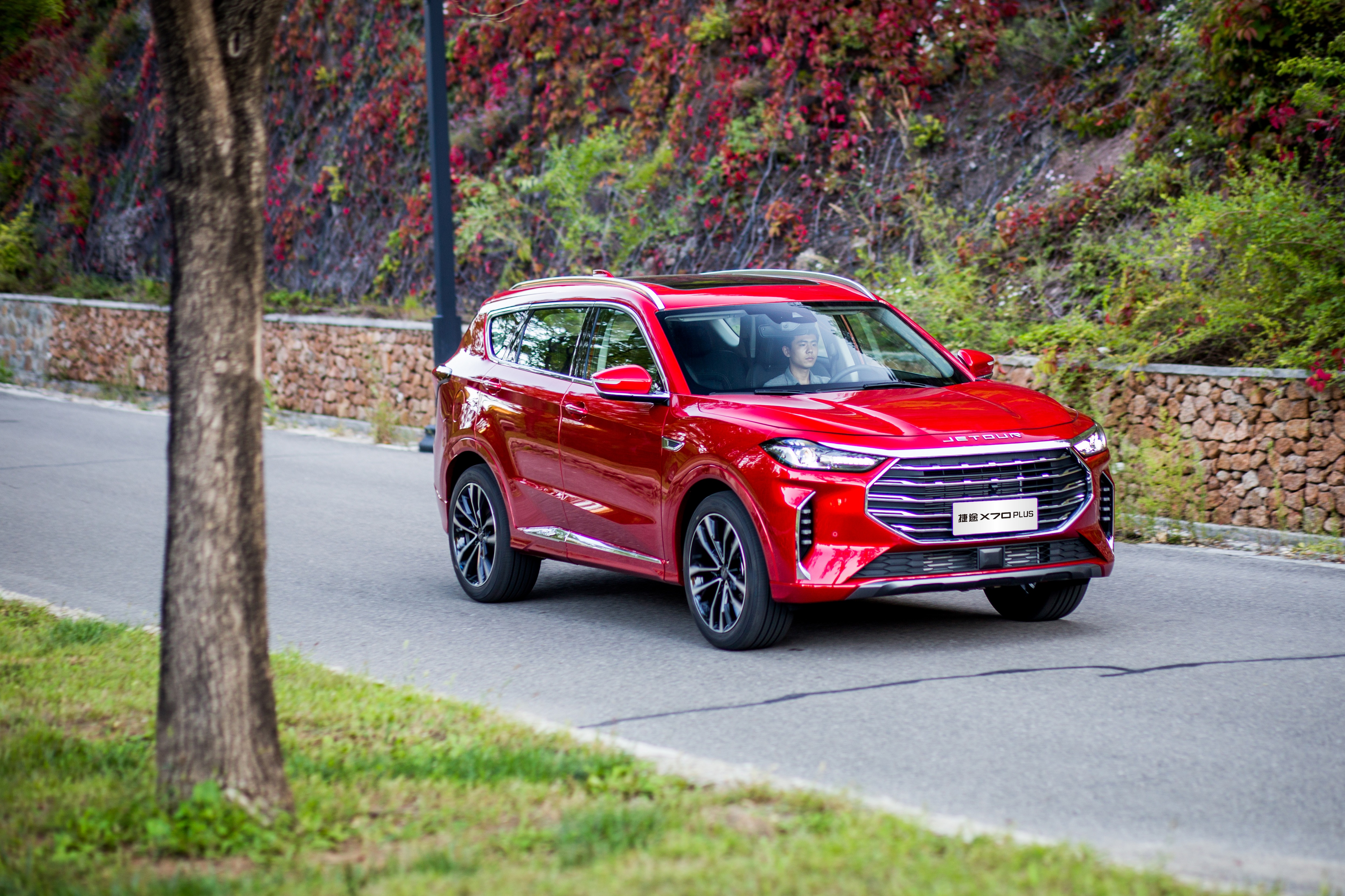 Red Jetour X70 Plus SUV driving on a road HD Wallpaper