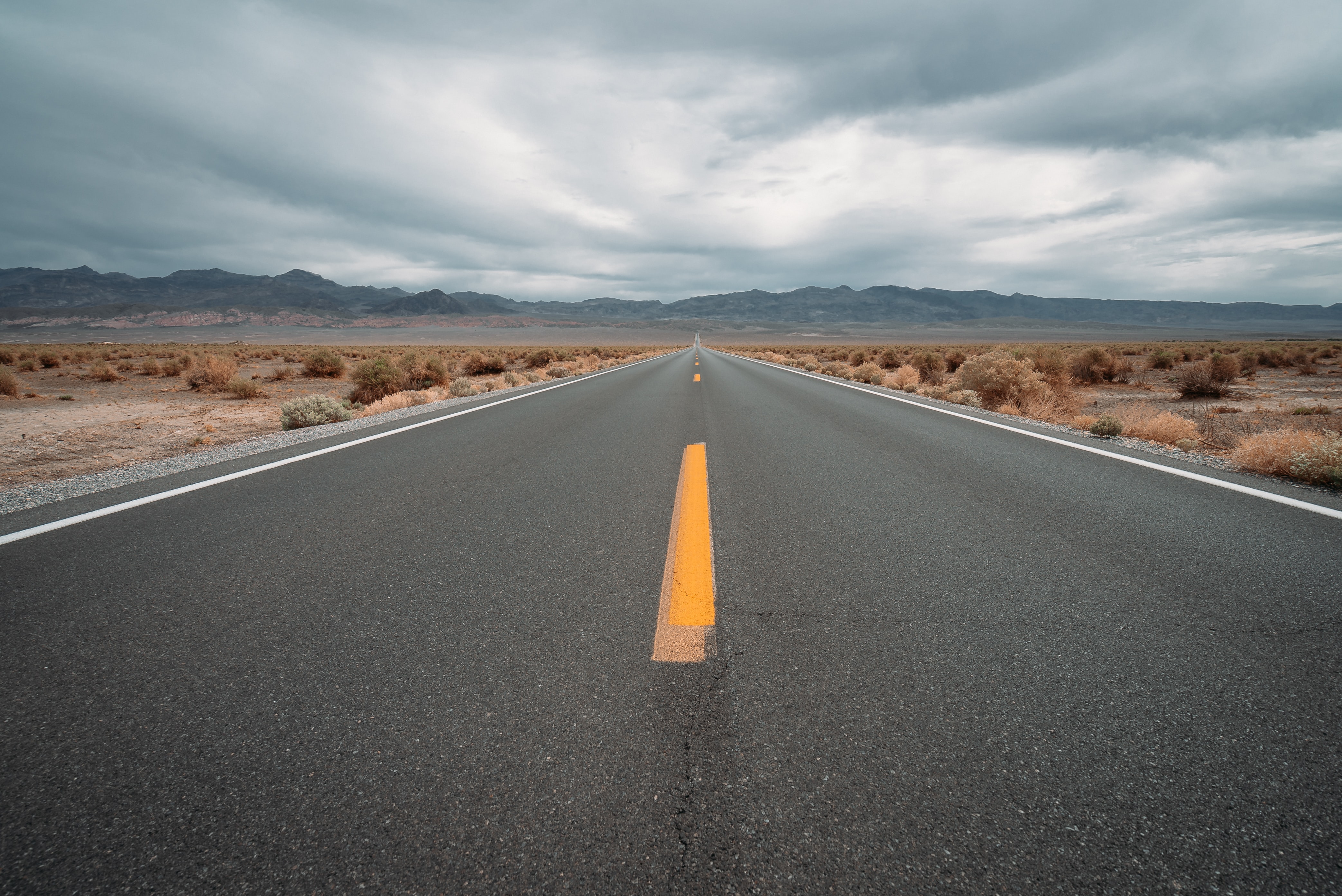 Desert highway under cloudy skies HD Wallpaper