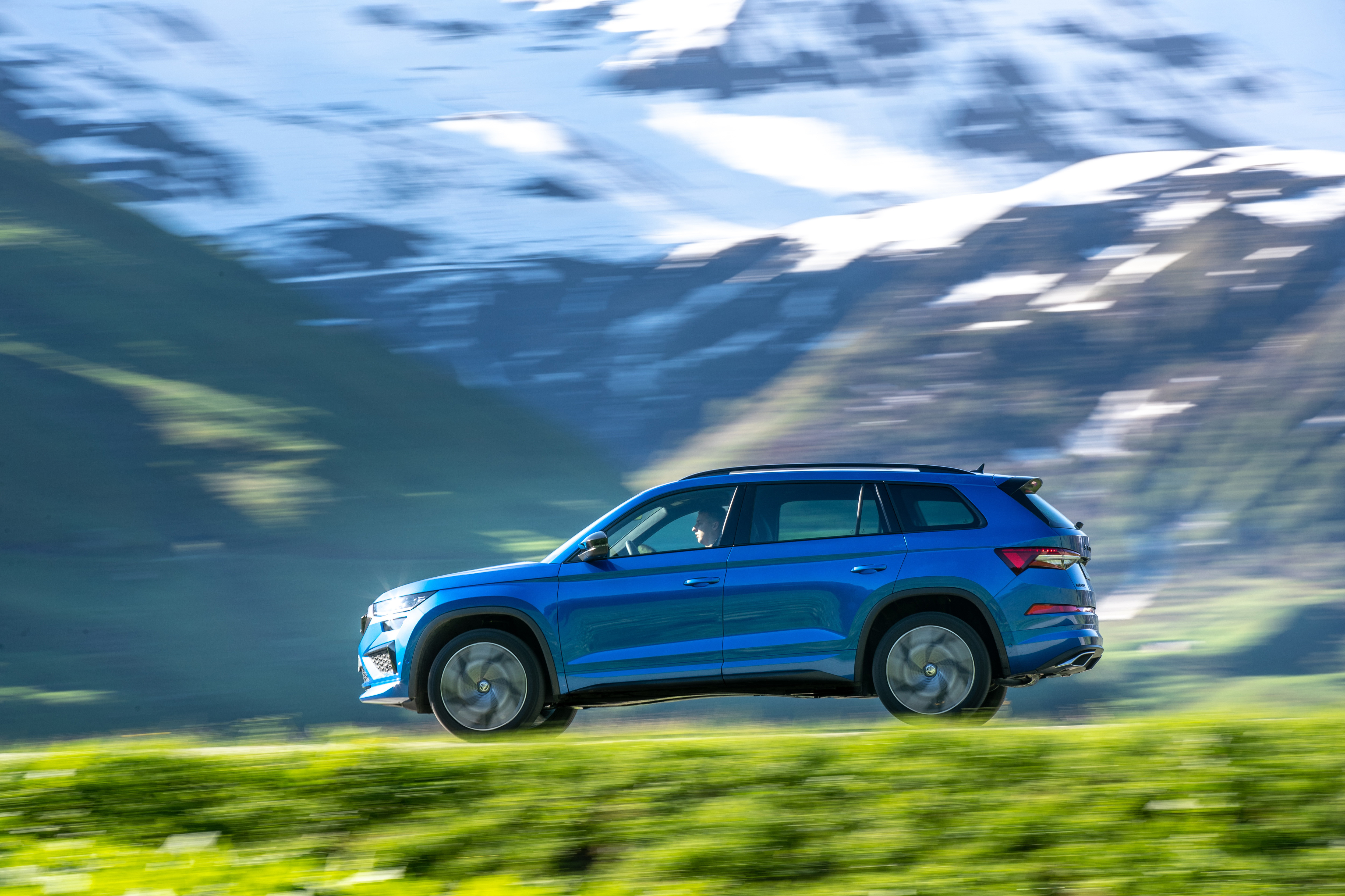 Blue Skoda Kodiaq RS driving through mountains HD Wallpaper