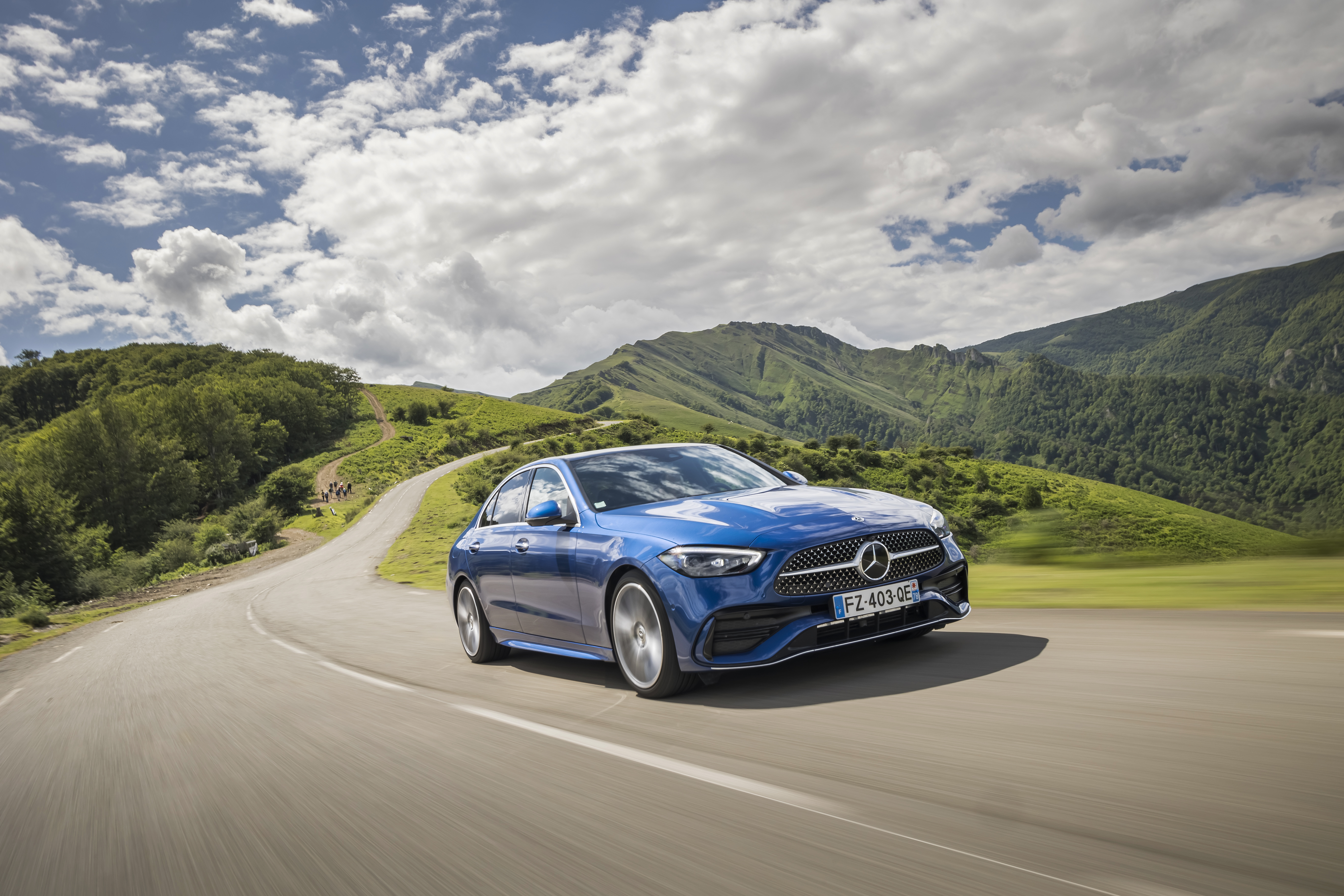 Blue Mercedes-Benz C 200 AMG Line driving on a scenic road HD Wallpaper