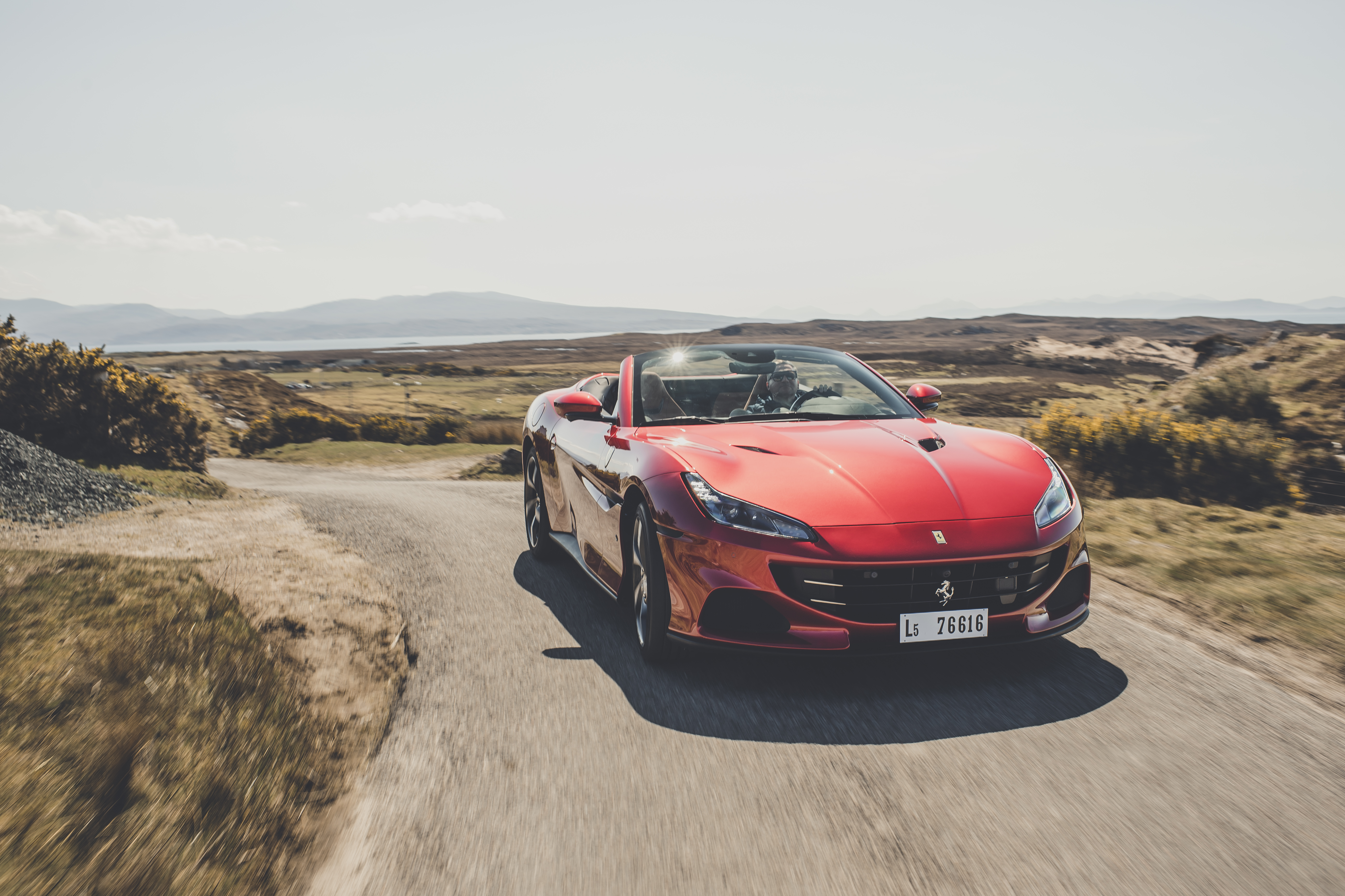 Red Ferrari Portofino M driving on a scenic road HD Wallpaper