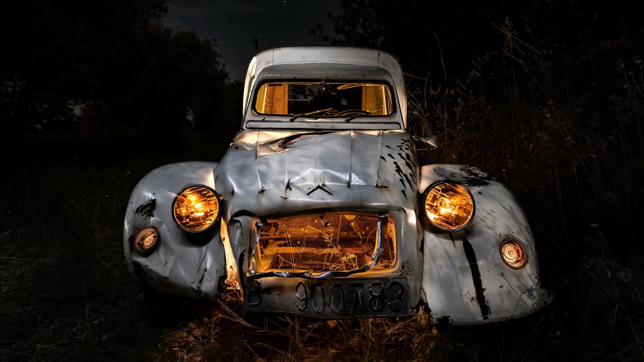 Wrecked Citroen 2CV car with glowing headlights at night HD Wallpaper