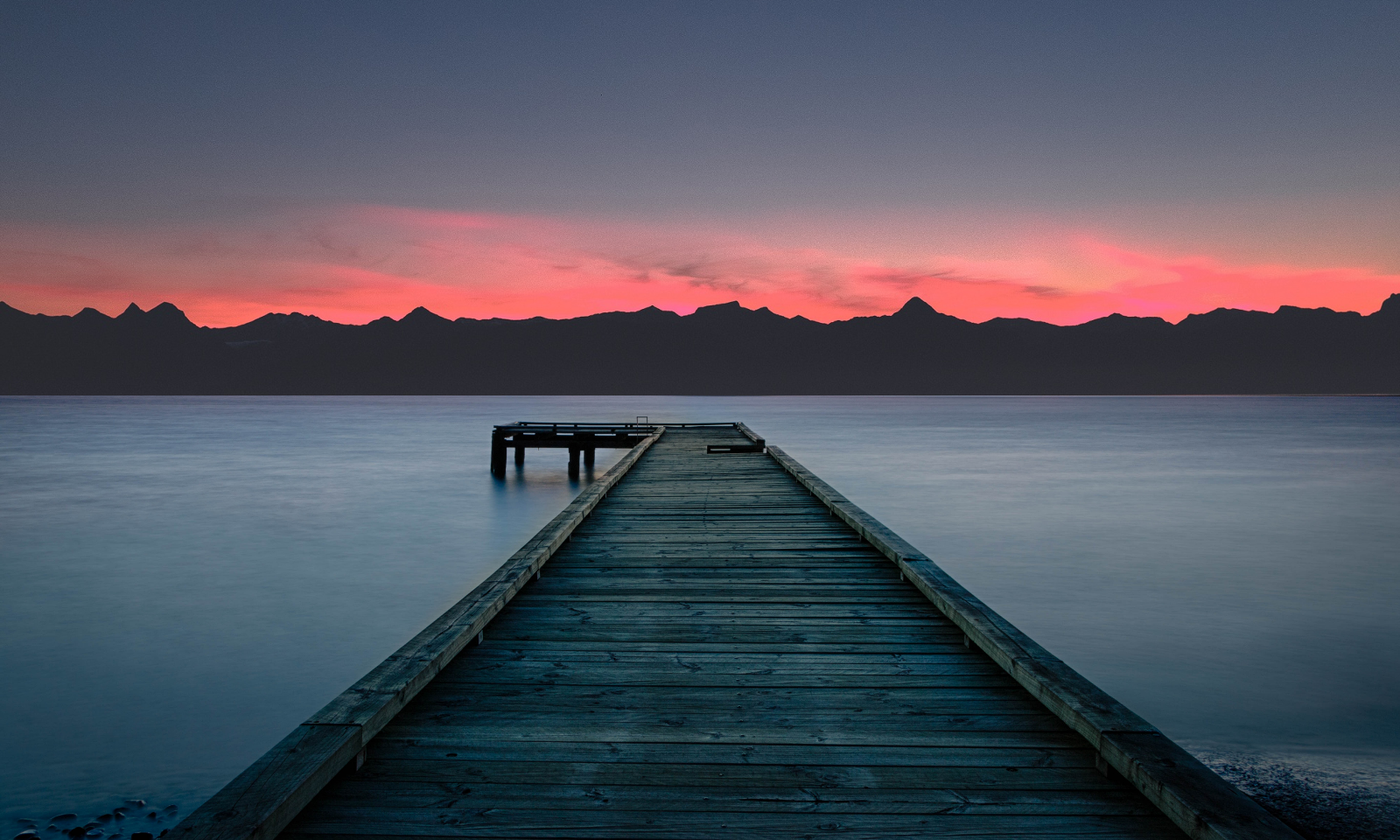 Wooden pier on a lake at sunset with mountains HD Wallpaper