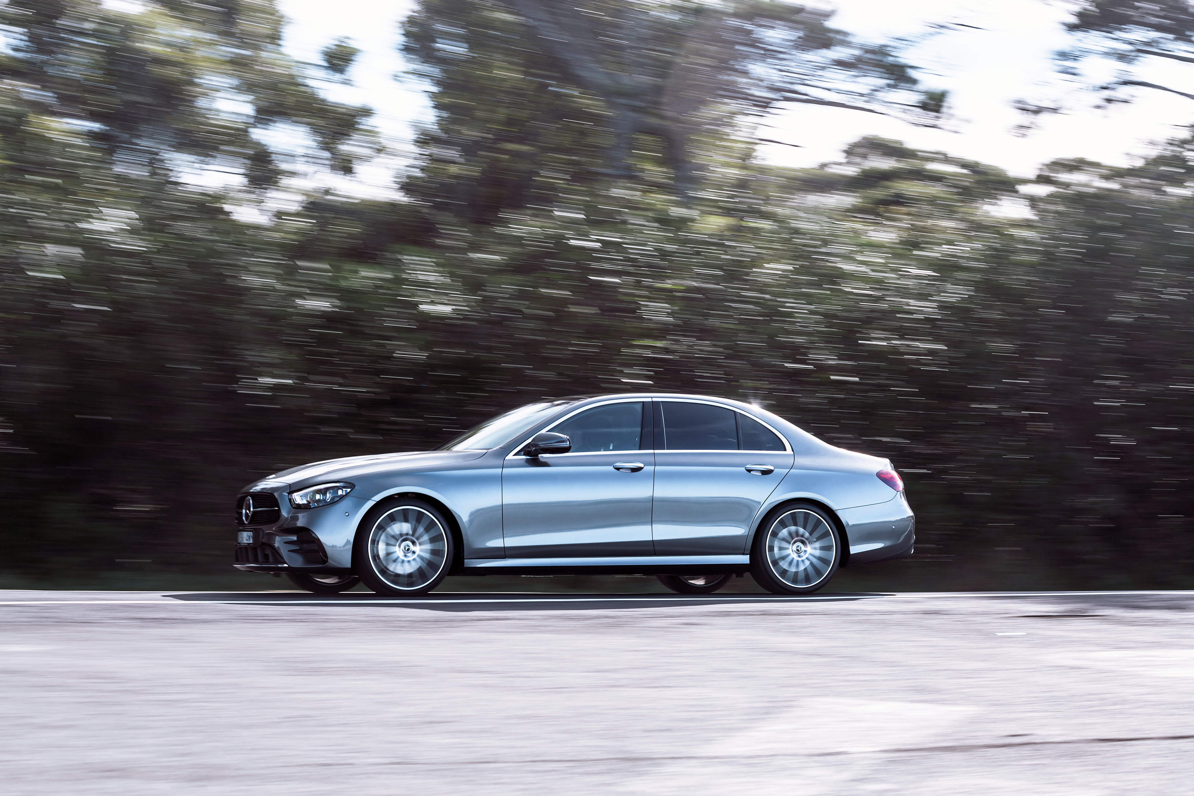 Silver Mercedes-Benz E 350 AMG Line driving on a road HD Wallpaper