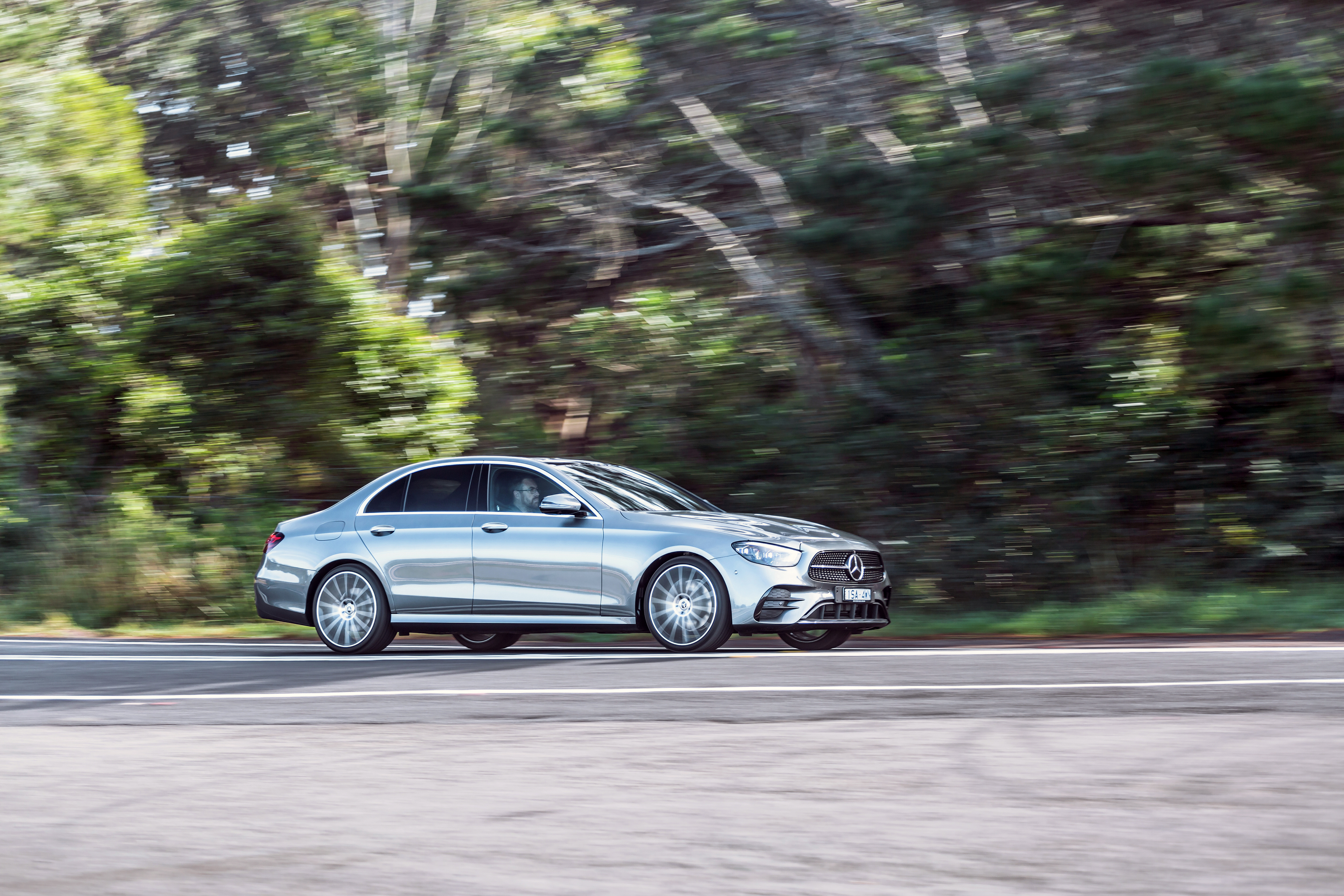 Silver Mercedes-Benz E 350 AMG Line driving on a road HD Wallpaper
