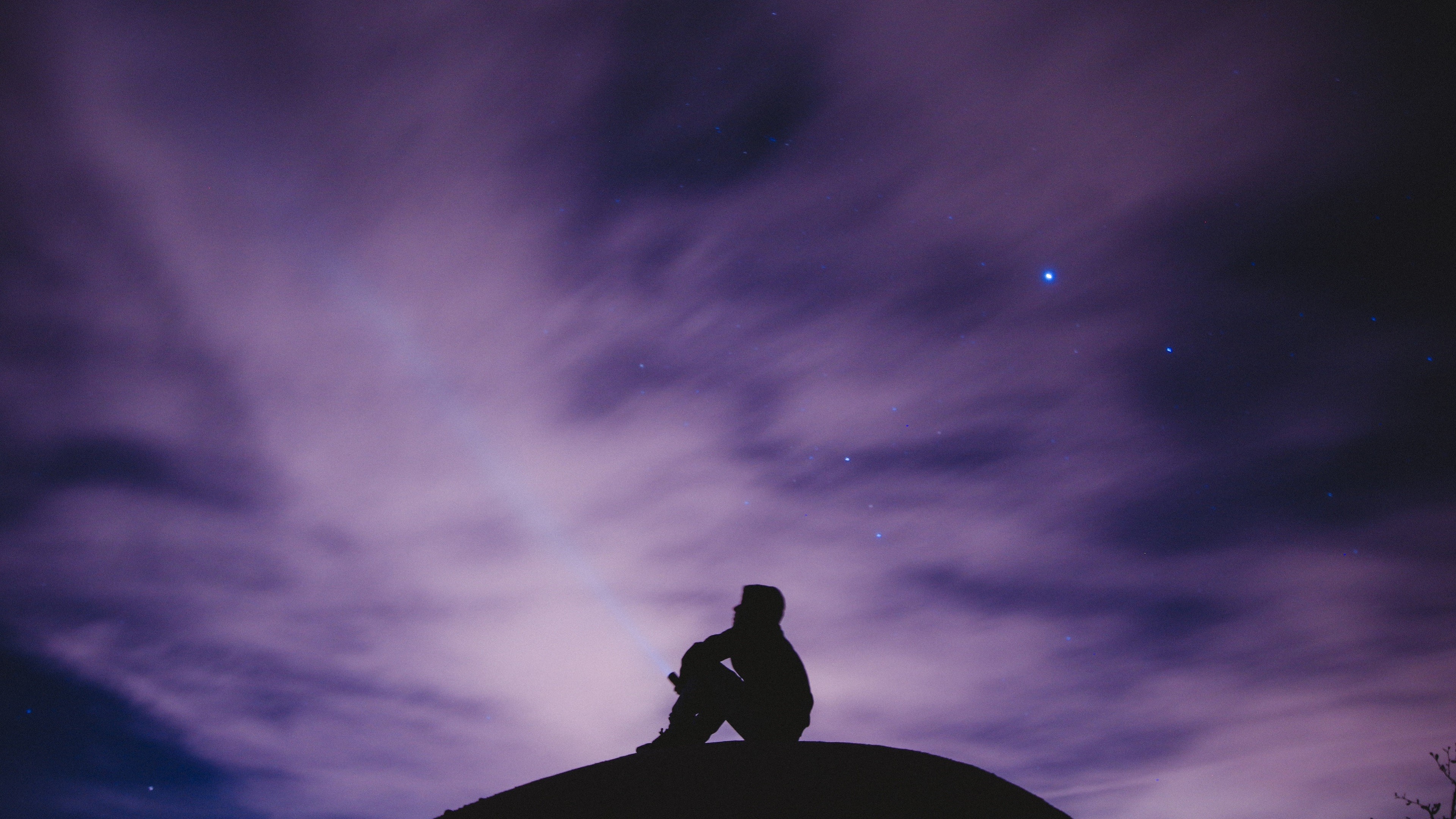 Silhouette of a person sitting on a hill under a starry sky HD Wallpaper