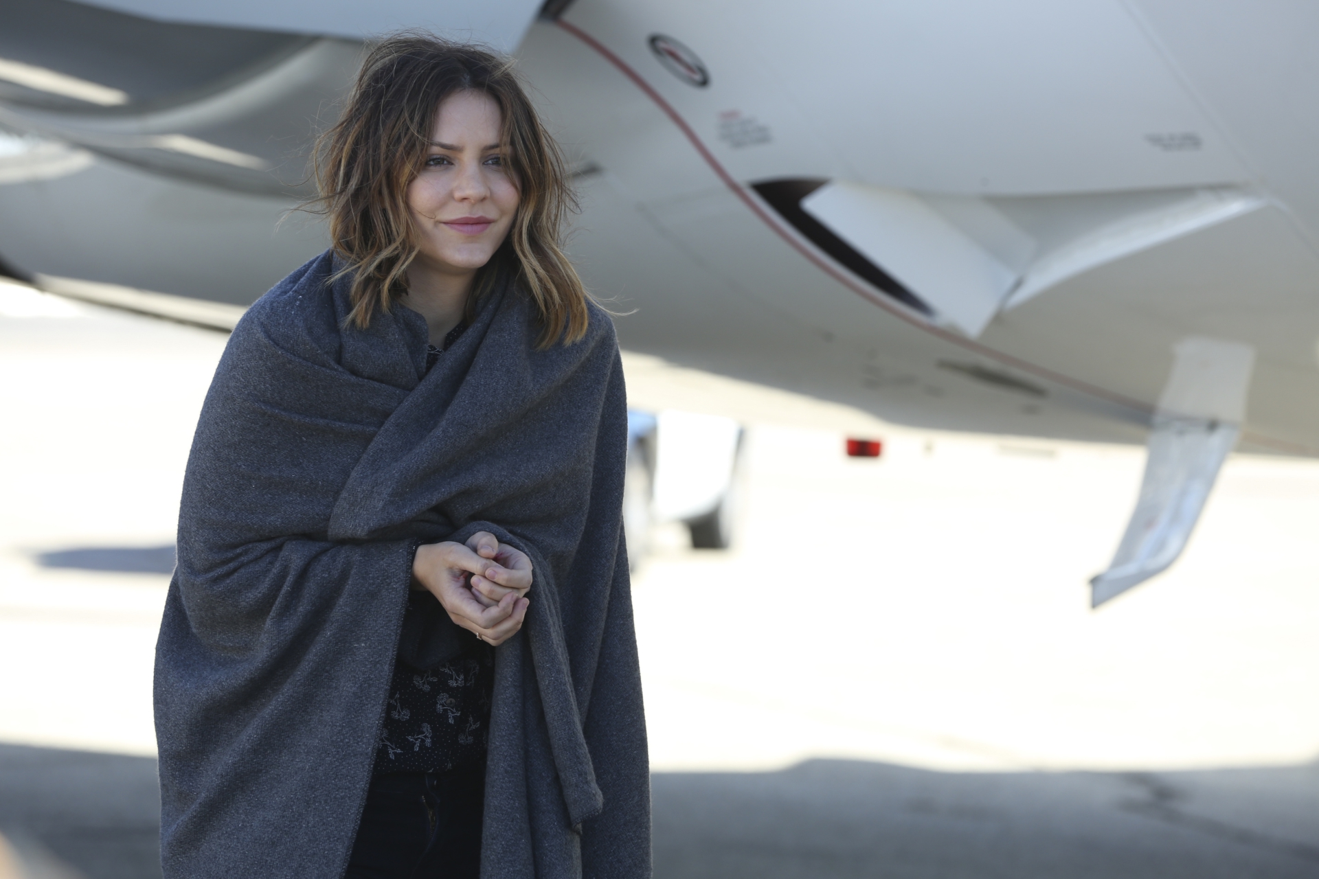 Katharine McPhee wrapped in a blanket near a private jet HD Wallpaper