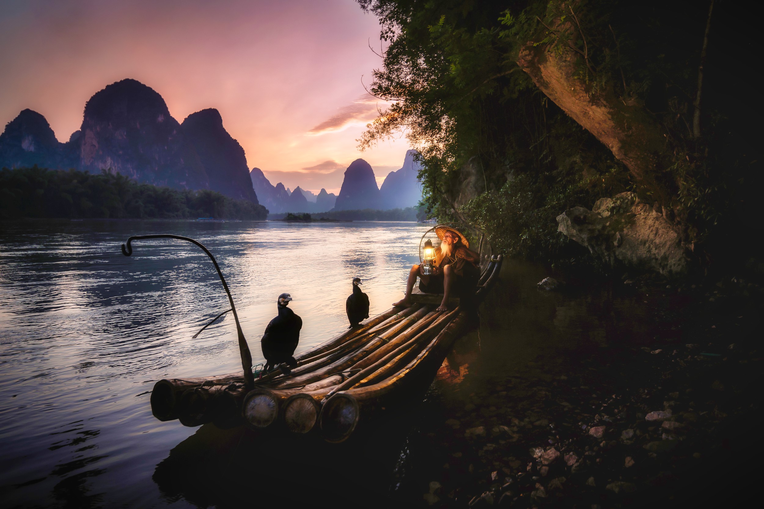 Fisherman with cormorants on a raft at sunset HD Wallpaper