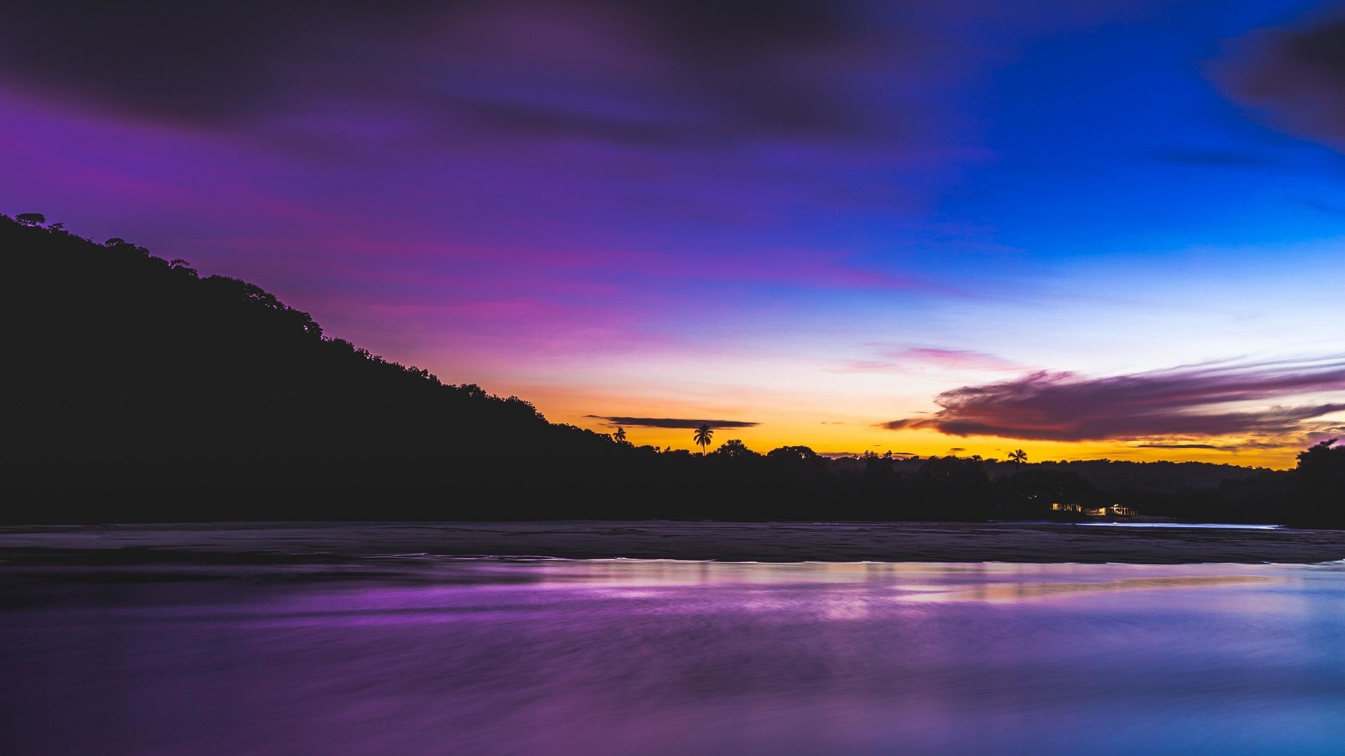 Purple and blue sunset over a lake and silhouetted hills HD Wallpaper