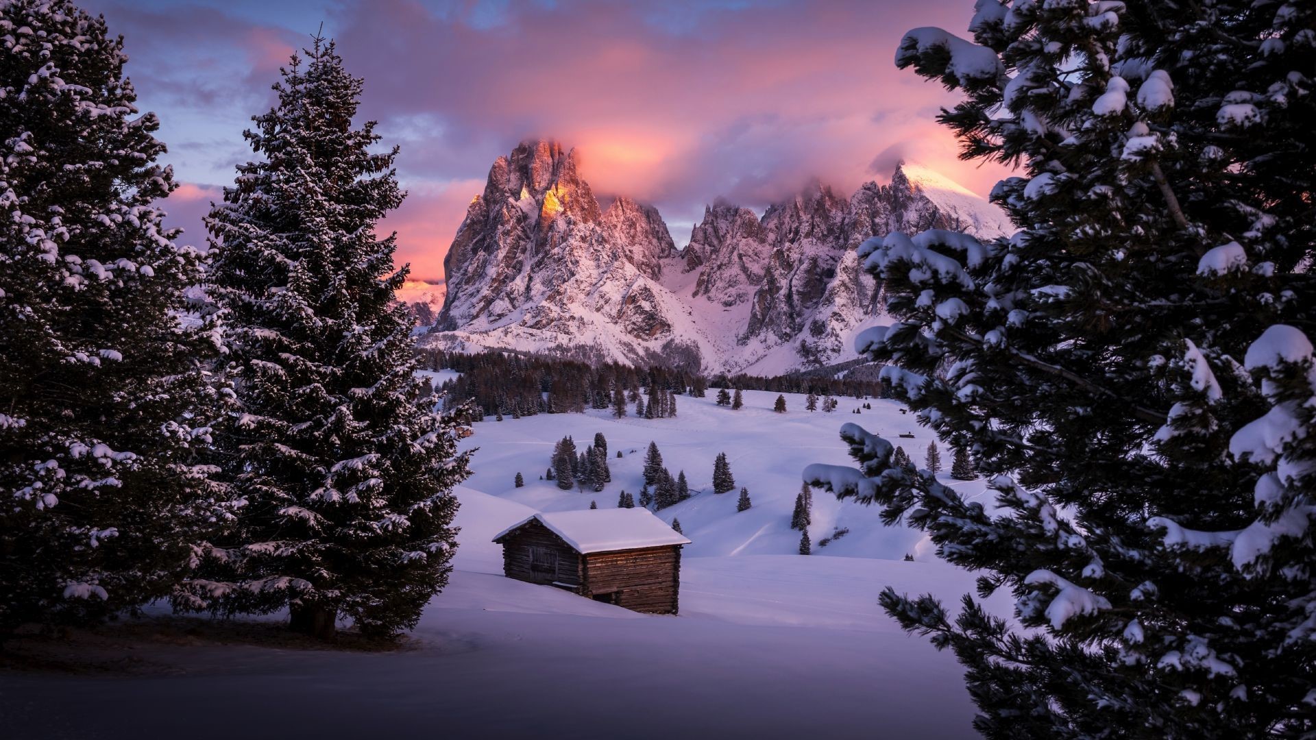 Snowy mountains and trees at sunset with a cabin HD Wallpaper
