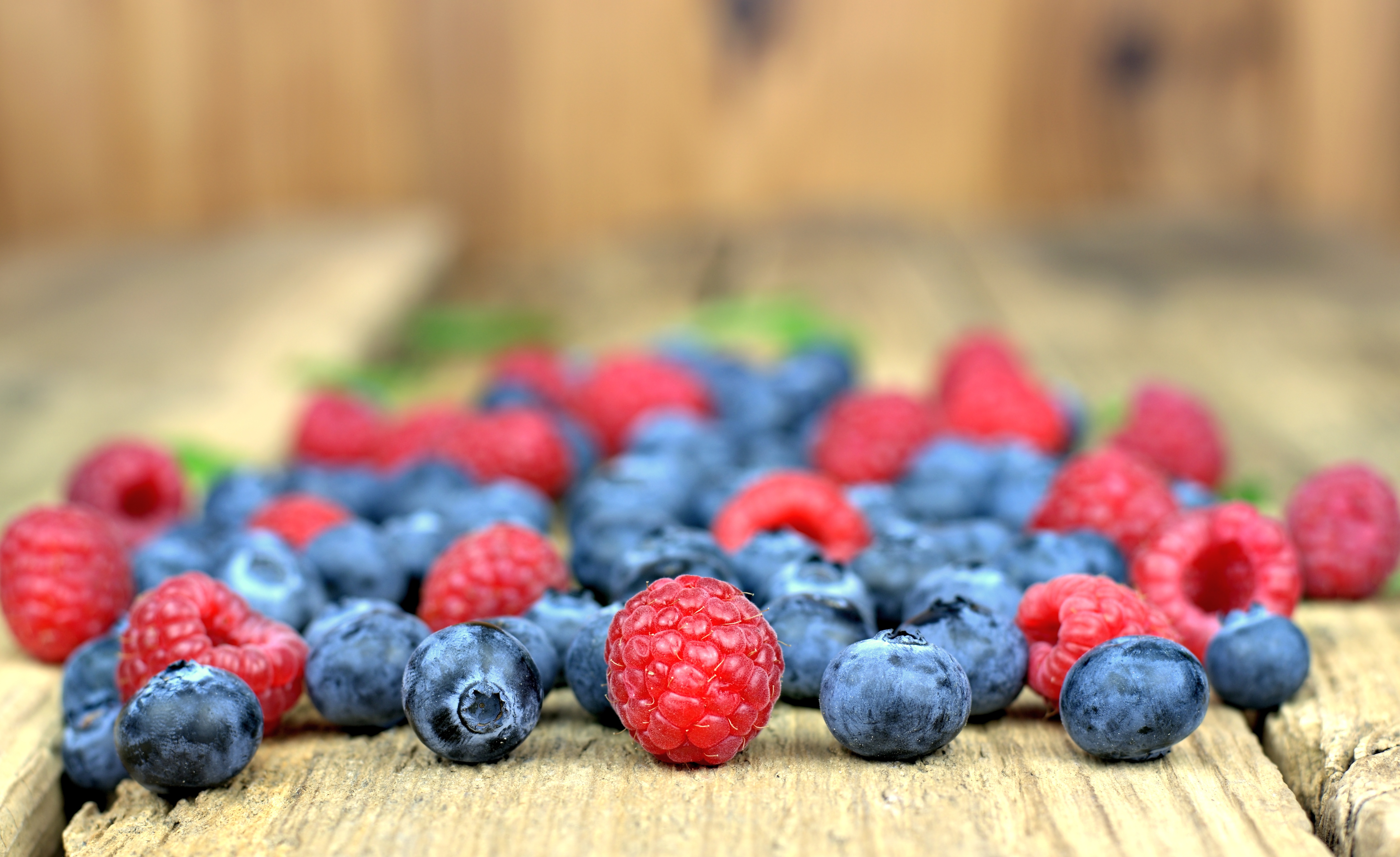 Raspberries and blueberries on a wooden surface HD Wallpaper