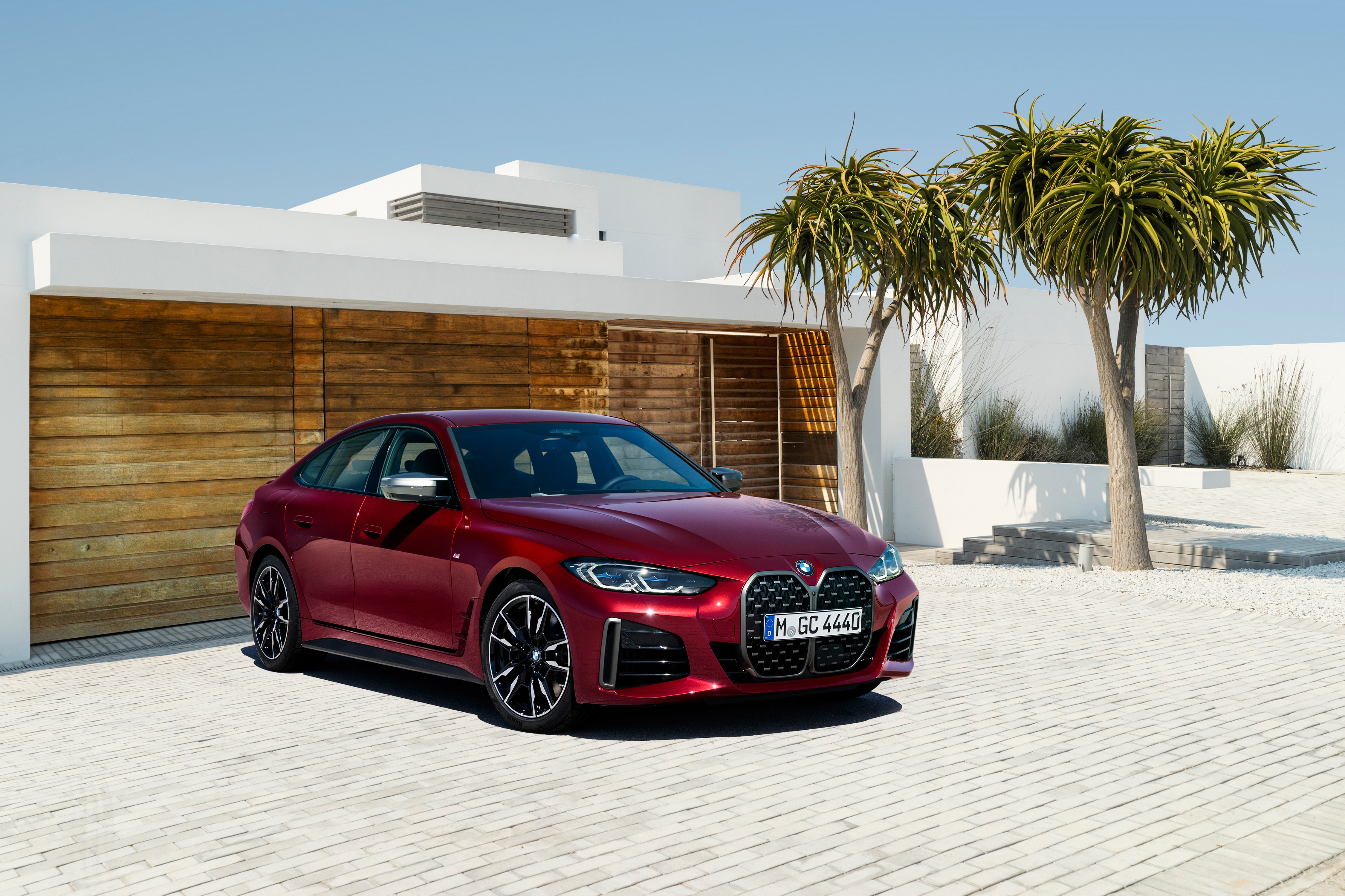 Red BMW M440i xDrive parked in front of a modern house HD Wallpaper