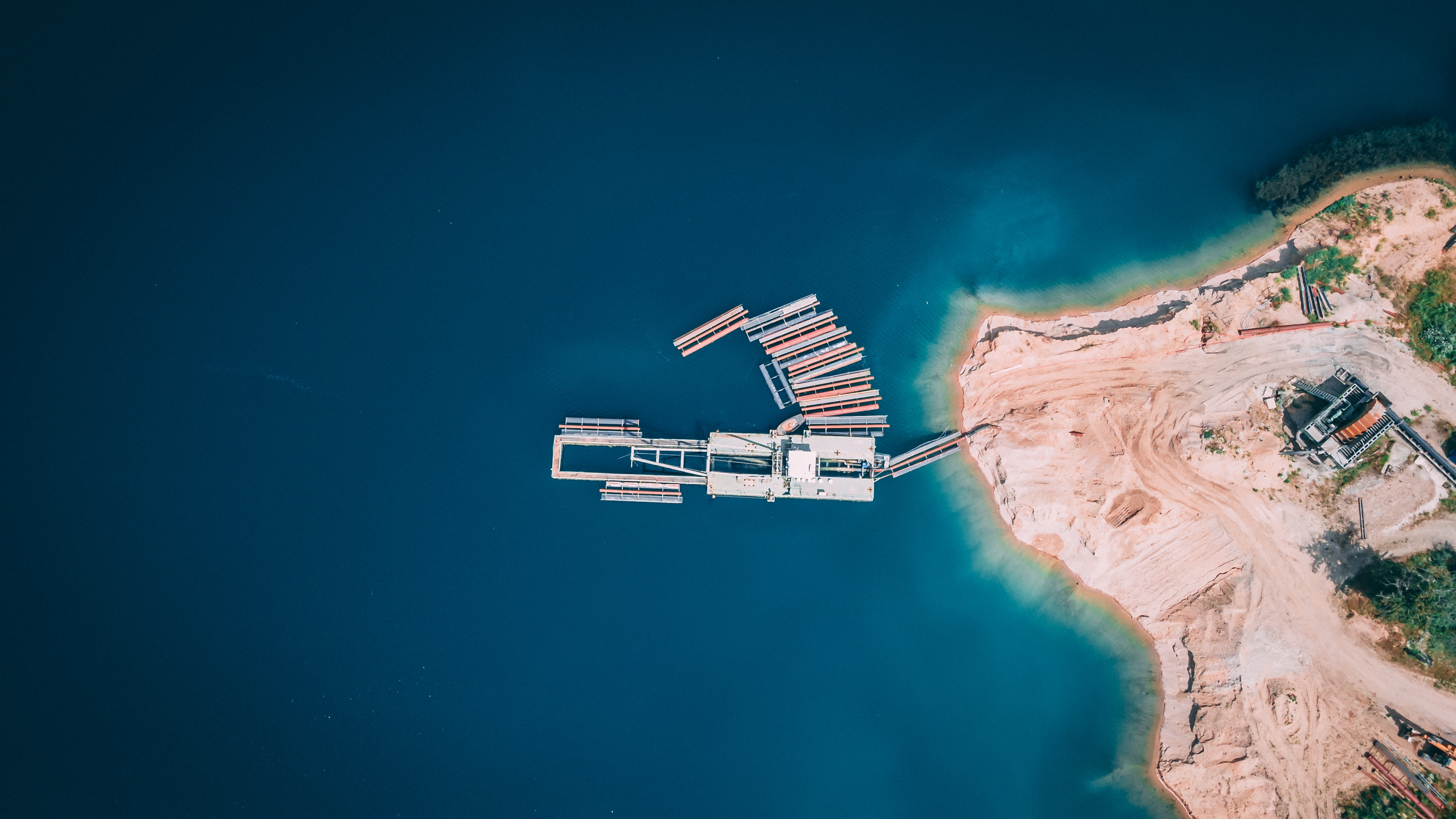 Aerial view of a dock and sandy coastline HD Wallpaper