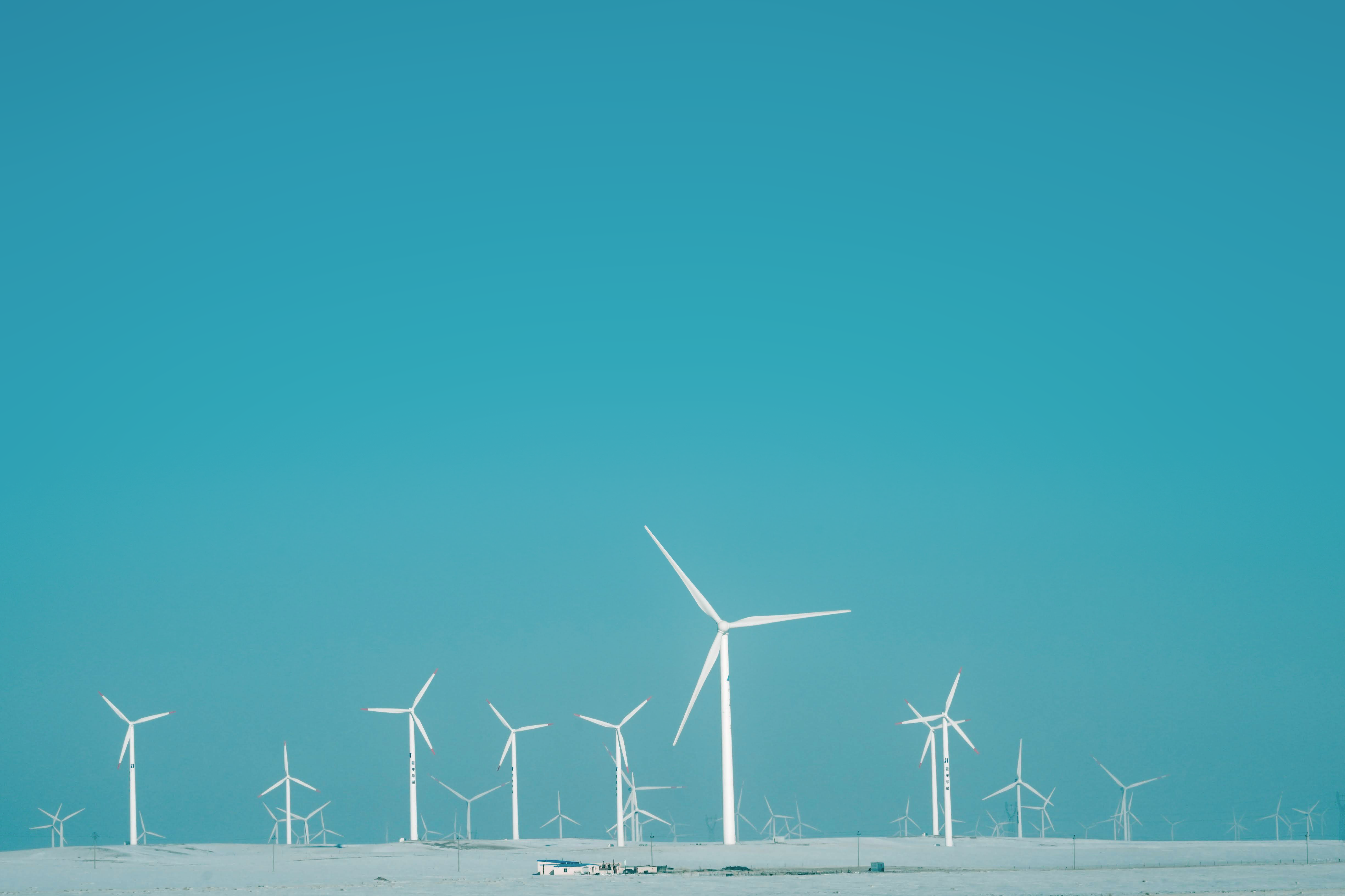 Wind turbines in a snowy landscape under a blue sky HD Wallpaper
