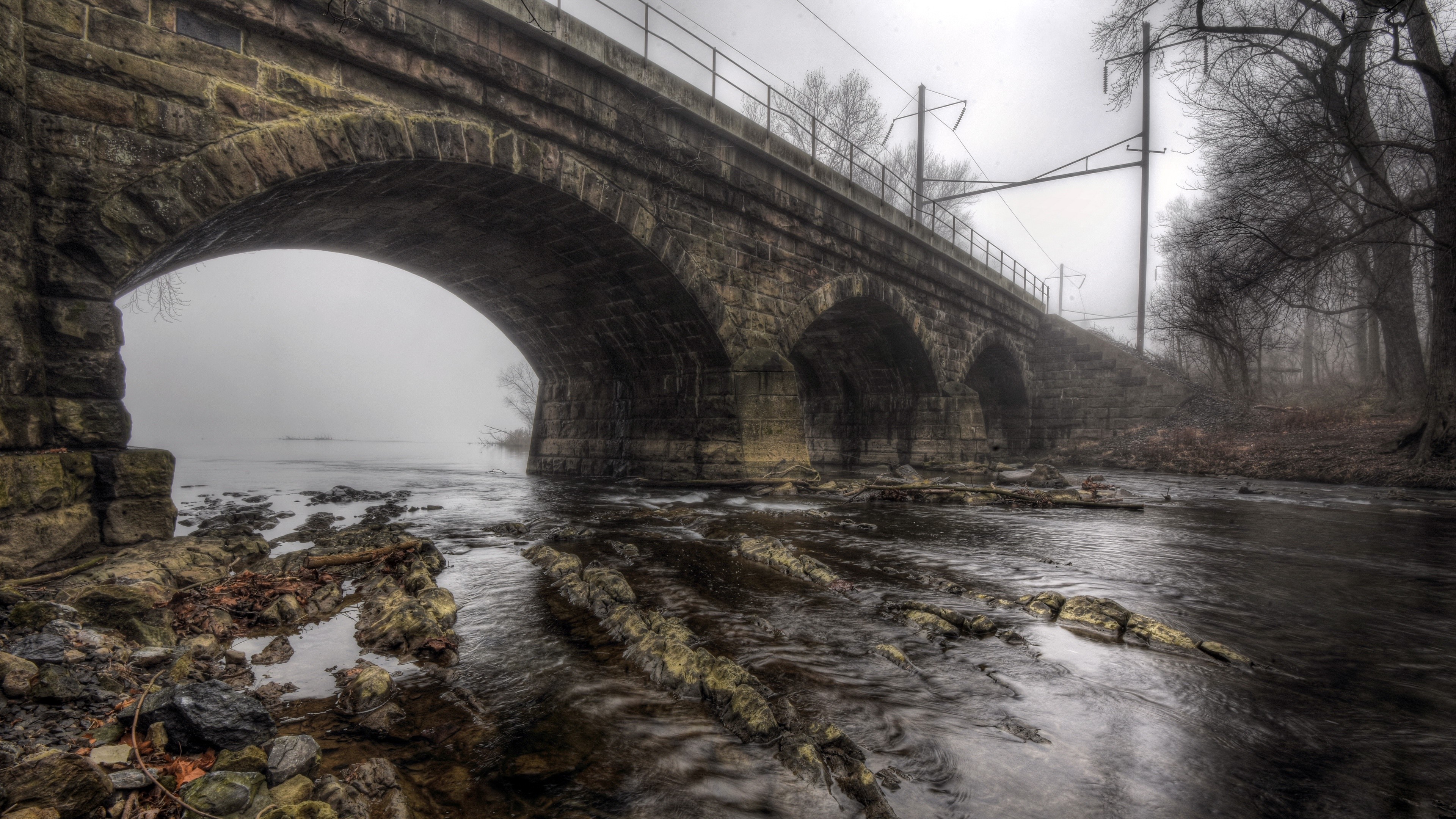 Old stone bridge over a river in fog HD Wallpaper