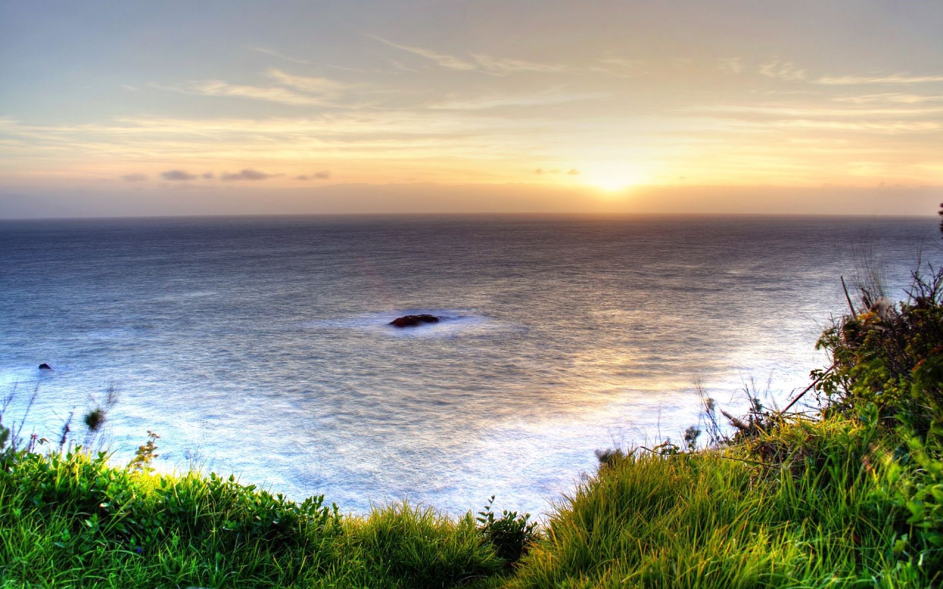 Ocean sunset with grassy cliffside HD Wallpaper