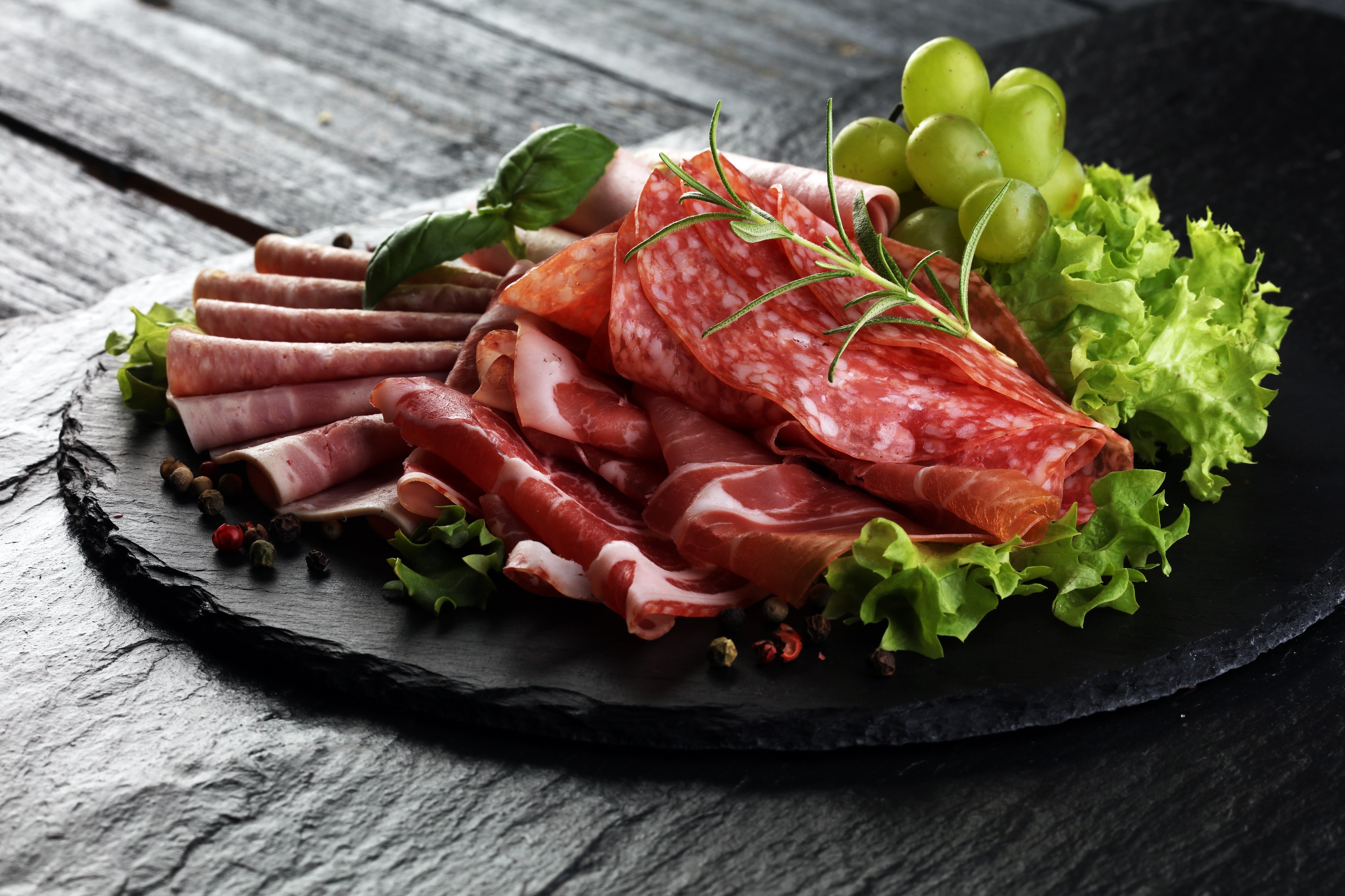 Charcuterie board with salami, prosciutto, grapes, and herbs HD Wallpaper