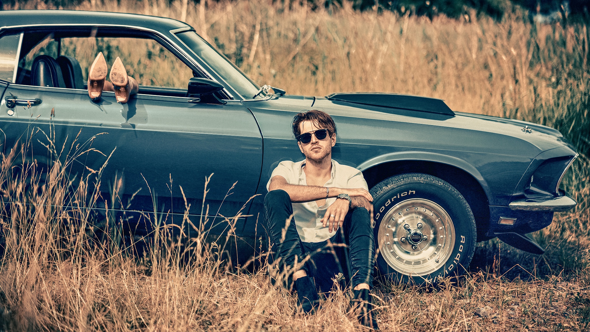 Man sitting by a classic car with heels in the window HD Wallpaper
