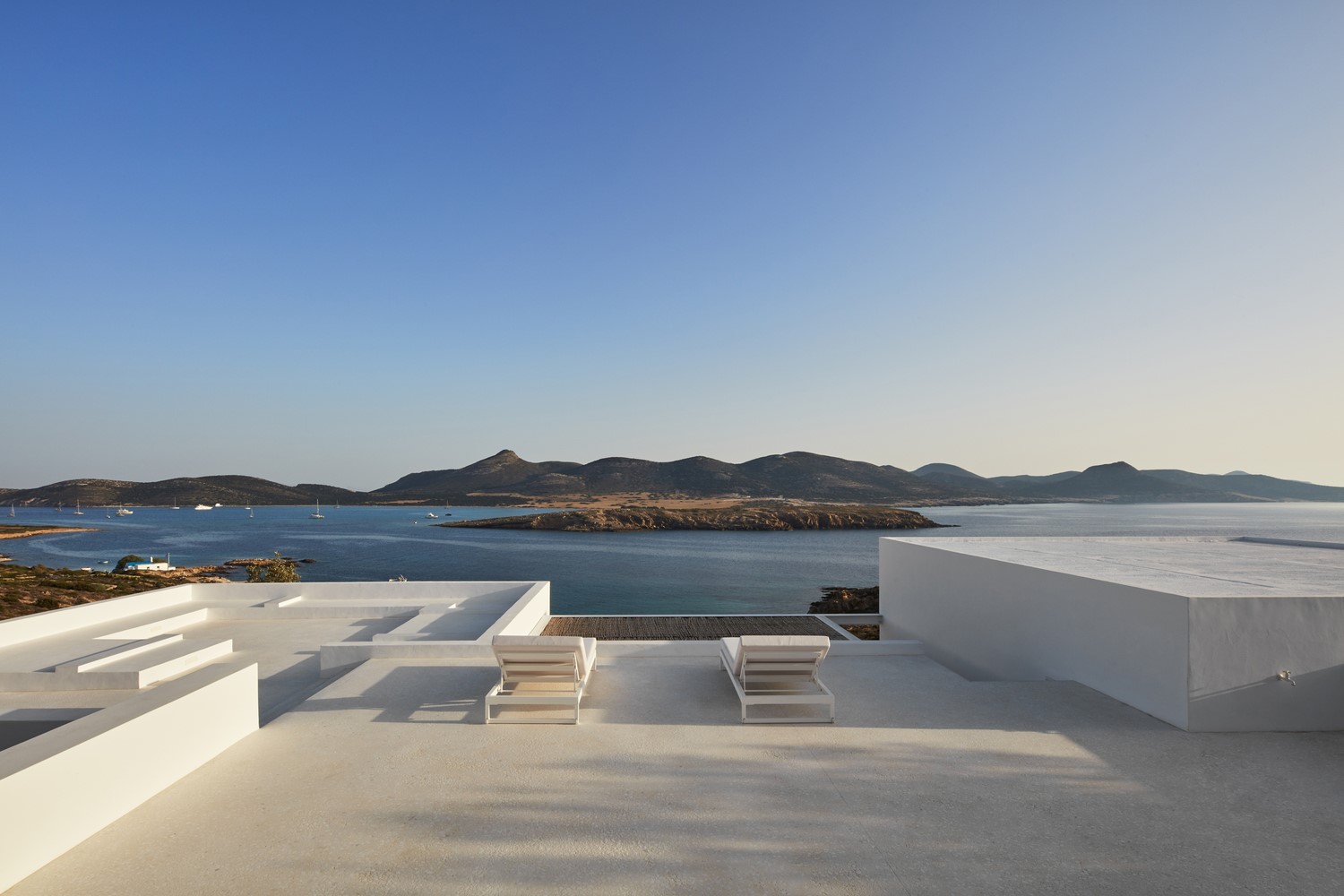 White terrace with lounge chairs overlooking the sea and mountains HD Wallpaper