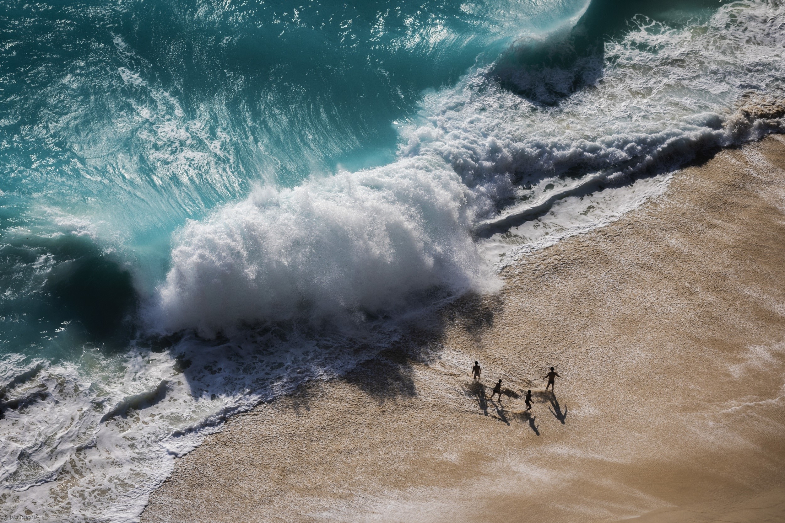 Aerial view of people on a sandy beach with crashing waves HD Wallpaper