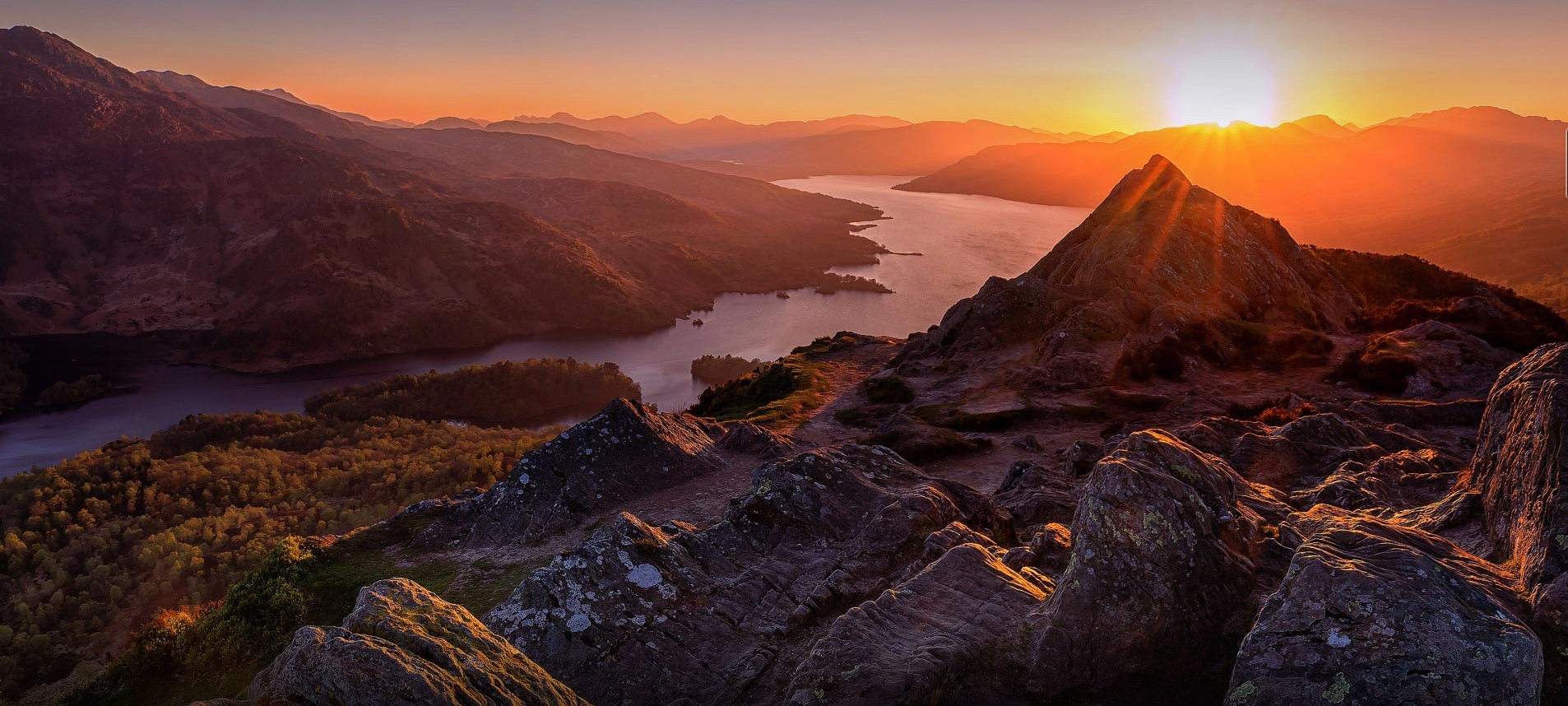 Sunrise over mountains and lake with rocky foreground HD Wallpaper