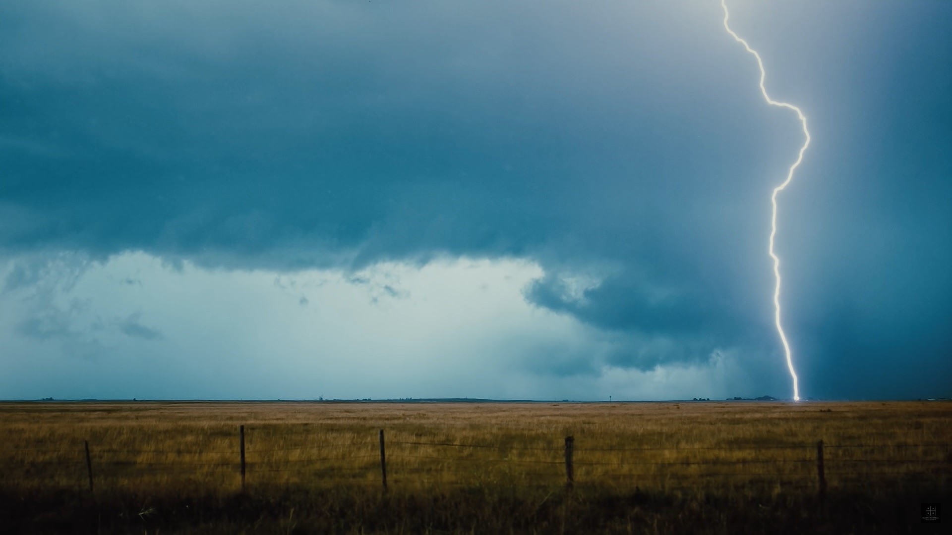 Lightning strike over a grassy field with storm clouds HD Wallpaper