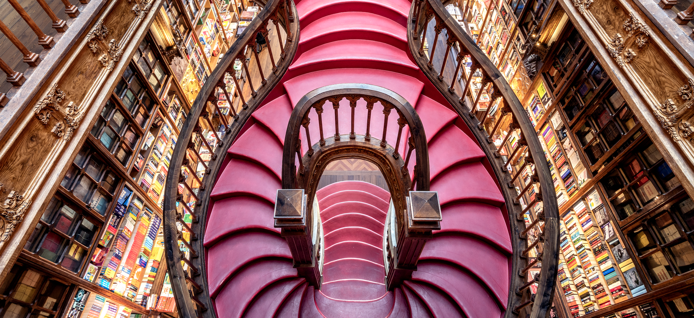 Interior of Livraria Lello bookstore with pink stairs and bookshelves HD Wallpaper