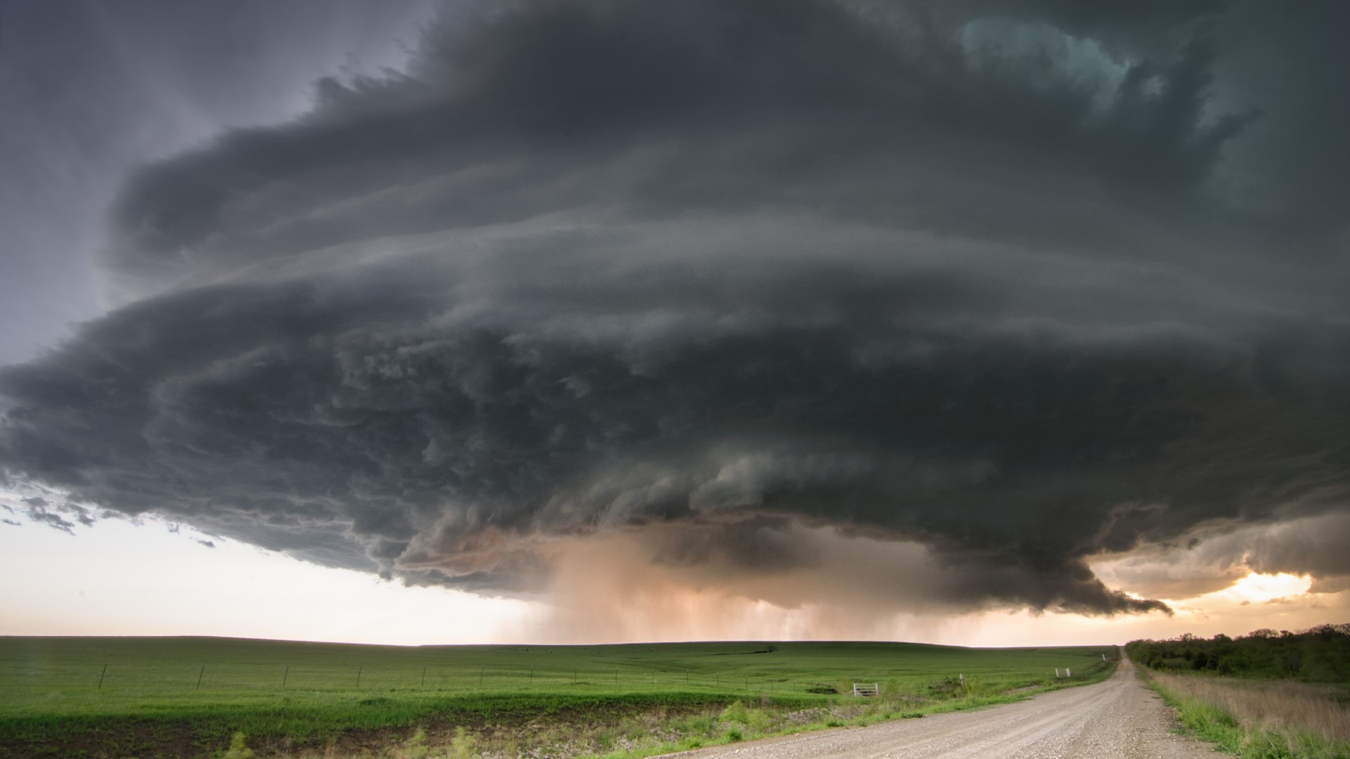 Storm clouds over a rural landscape with a dirt road HD Wallpaper