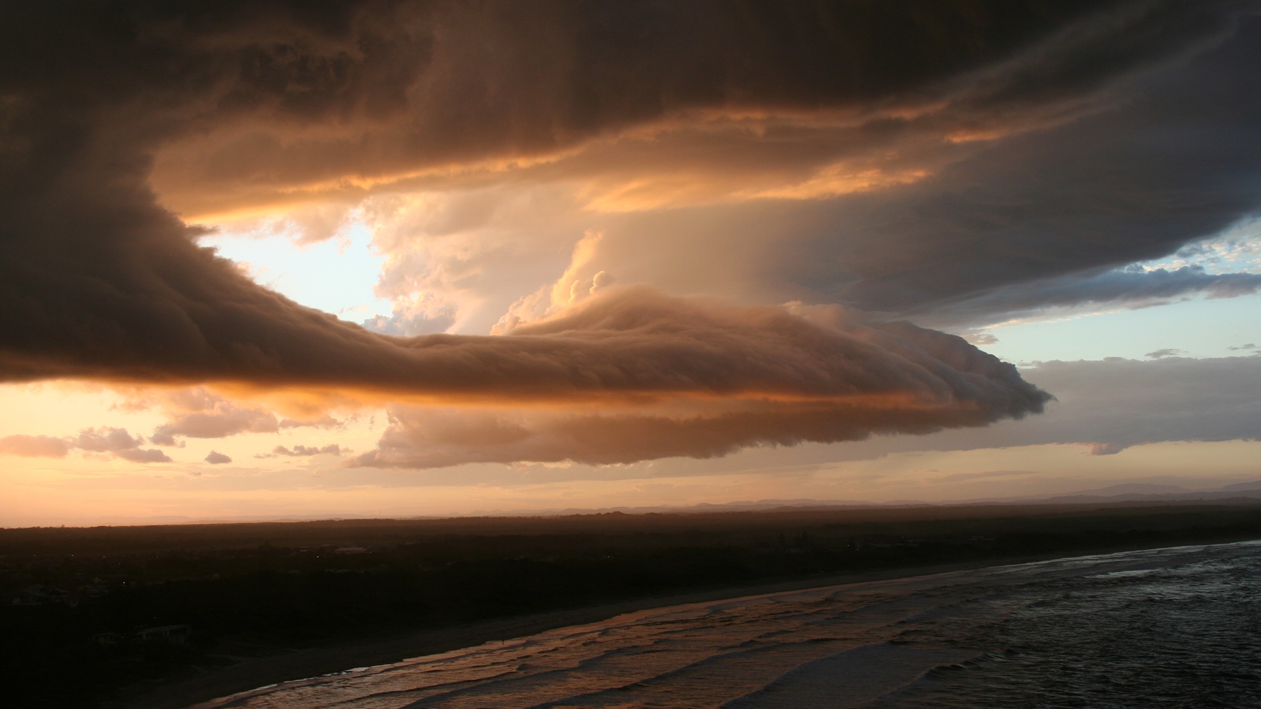 Dramatic storm clouds over a beach at sunset HD Wallpaper