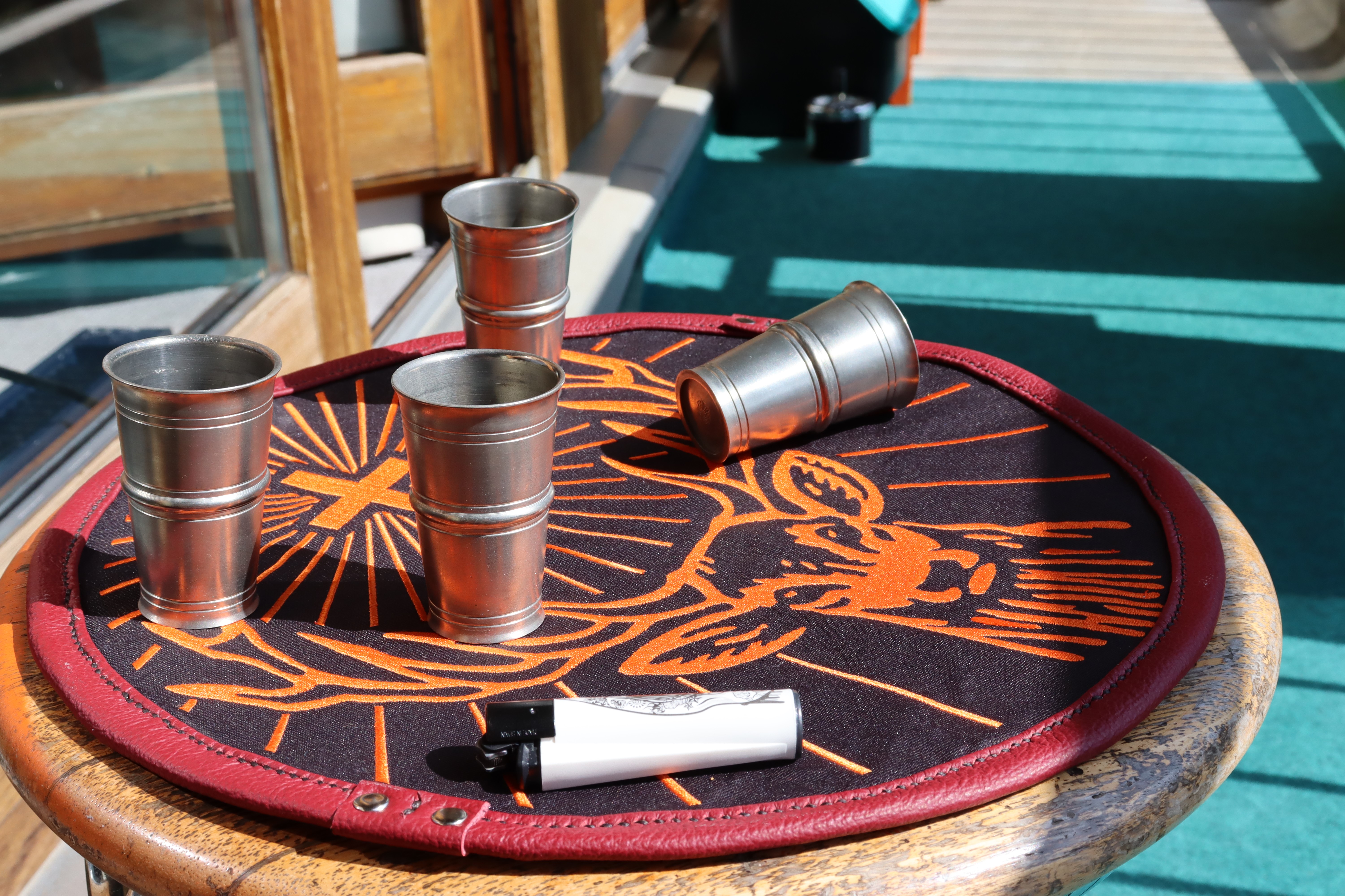 Four Jägermeister shot glasses and a lighter on a leather mat HD Wallpaper