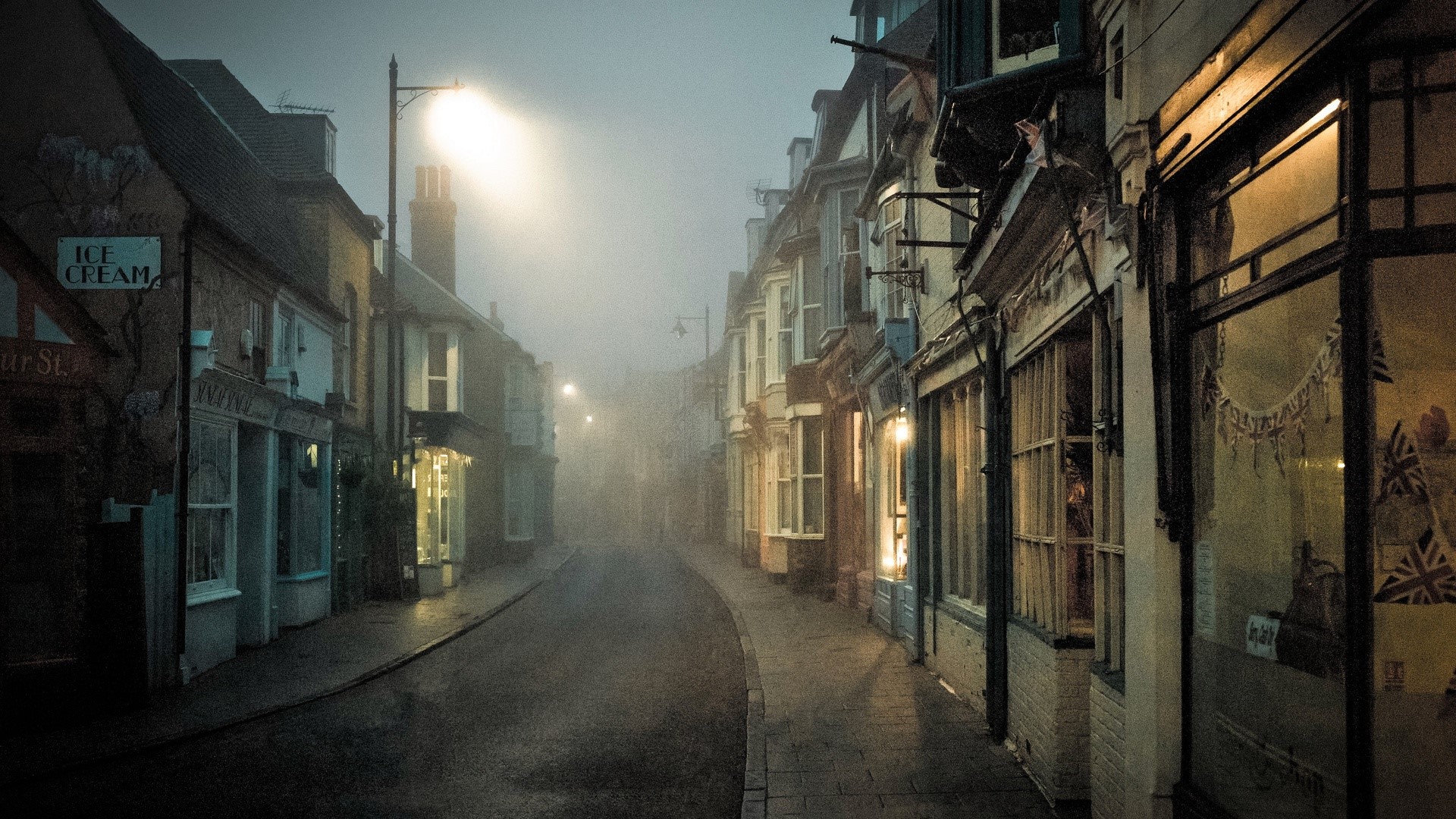 Misty street with shops and streetlights in England HD Wallpaper