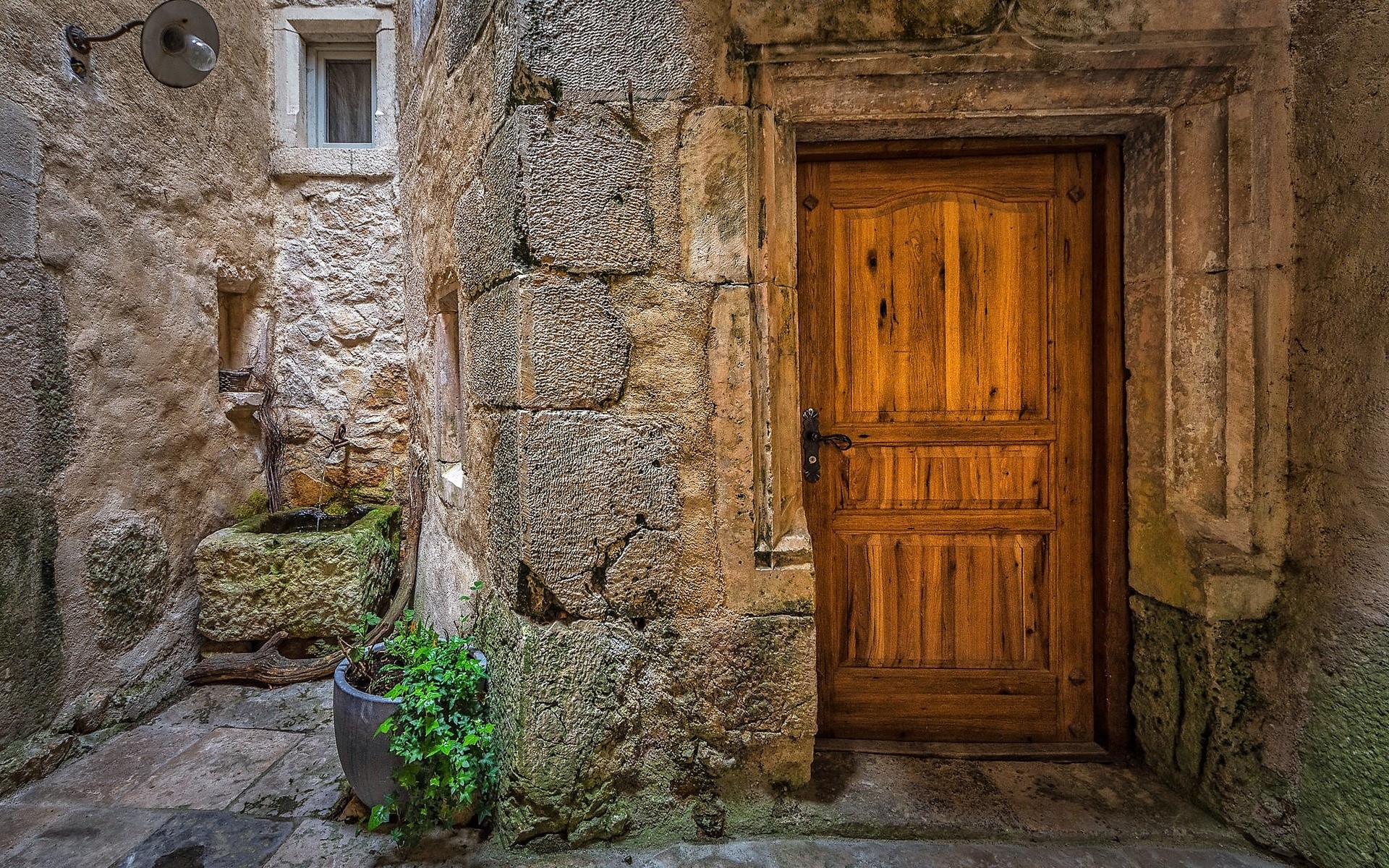 Old stone alley with wooden door and fountain HD Wallpaper