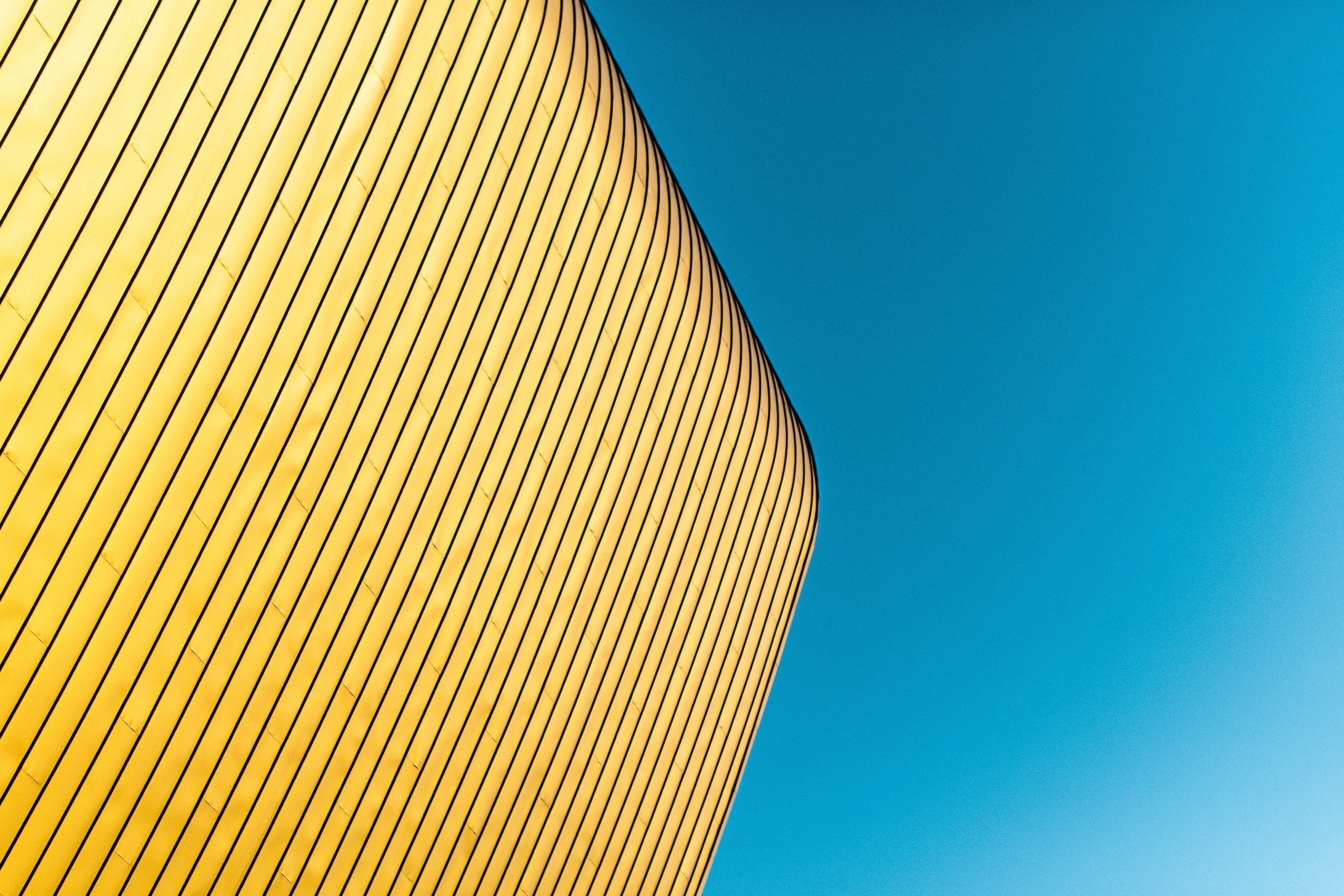 Minimalist yellow building facade against a blue sky HD Wallpaper
