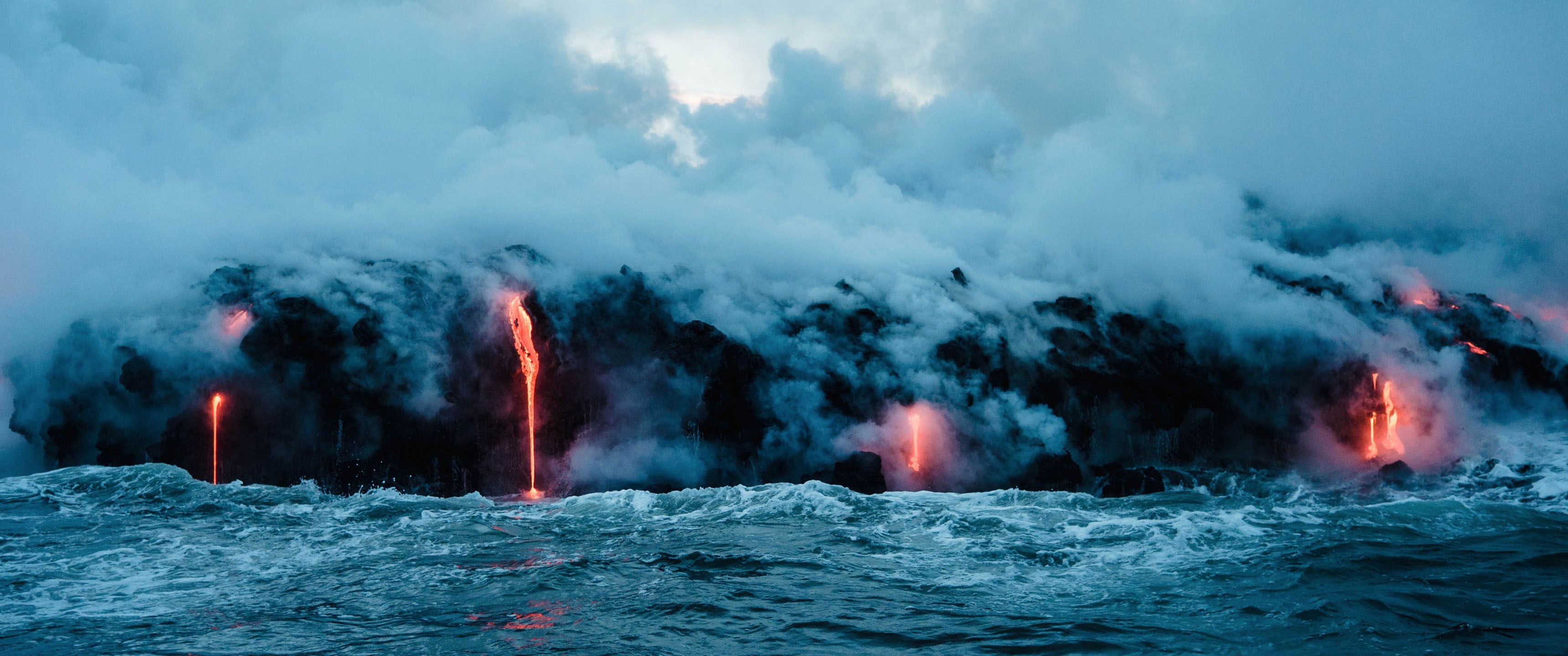Lava flows into the ocean with steam and waves HD Wallpaper