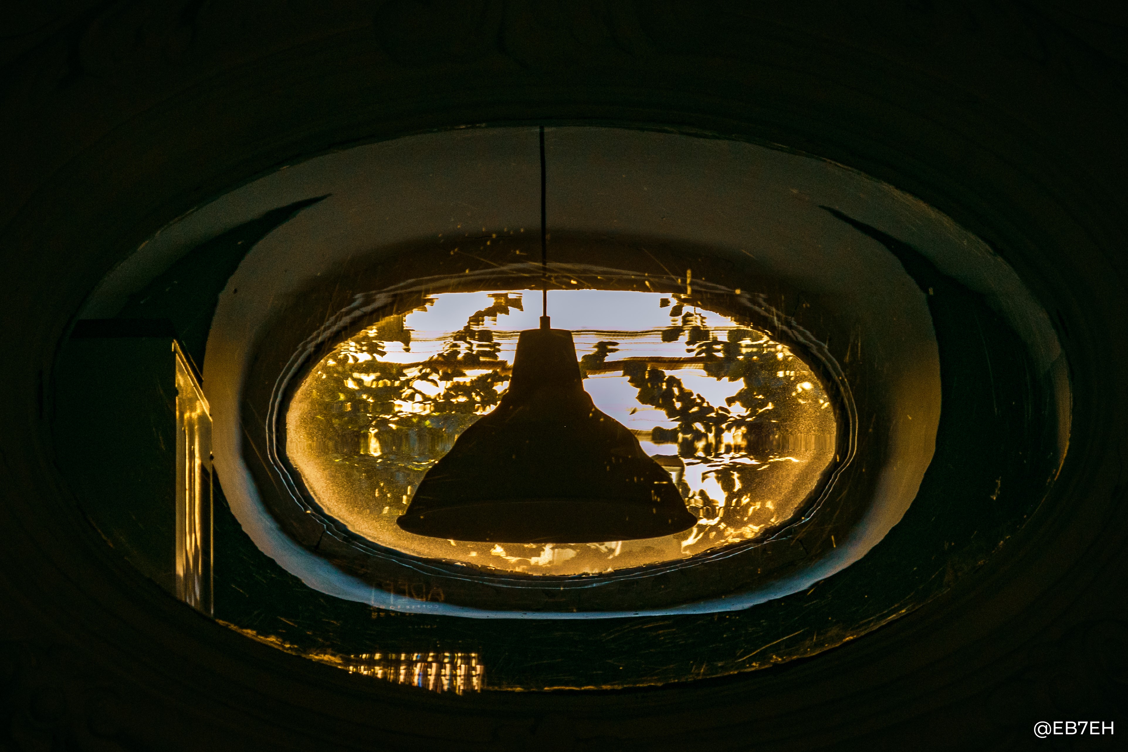 Lamp hanging in oval window with golden light HD Wallpaper