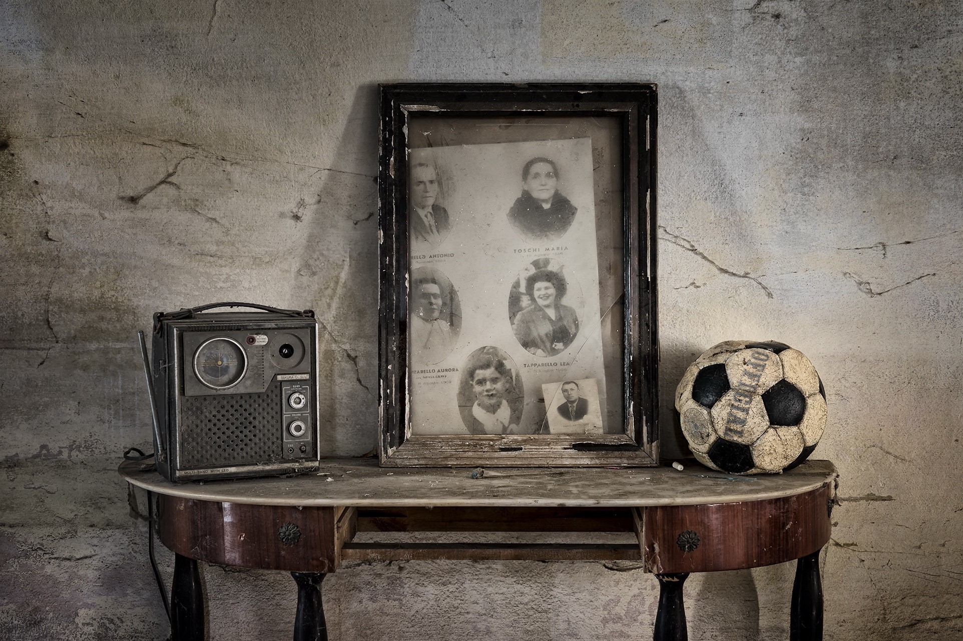 Old radio, framed family photos, and soccer ball on a table HD Wallpaper