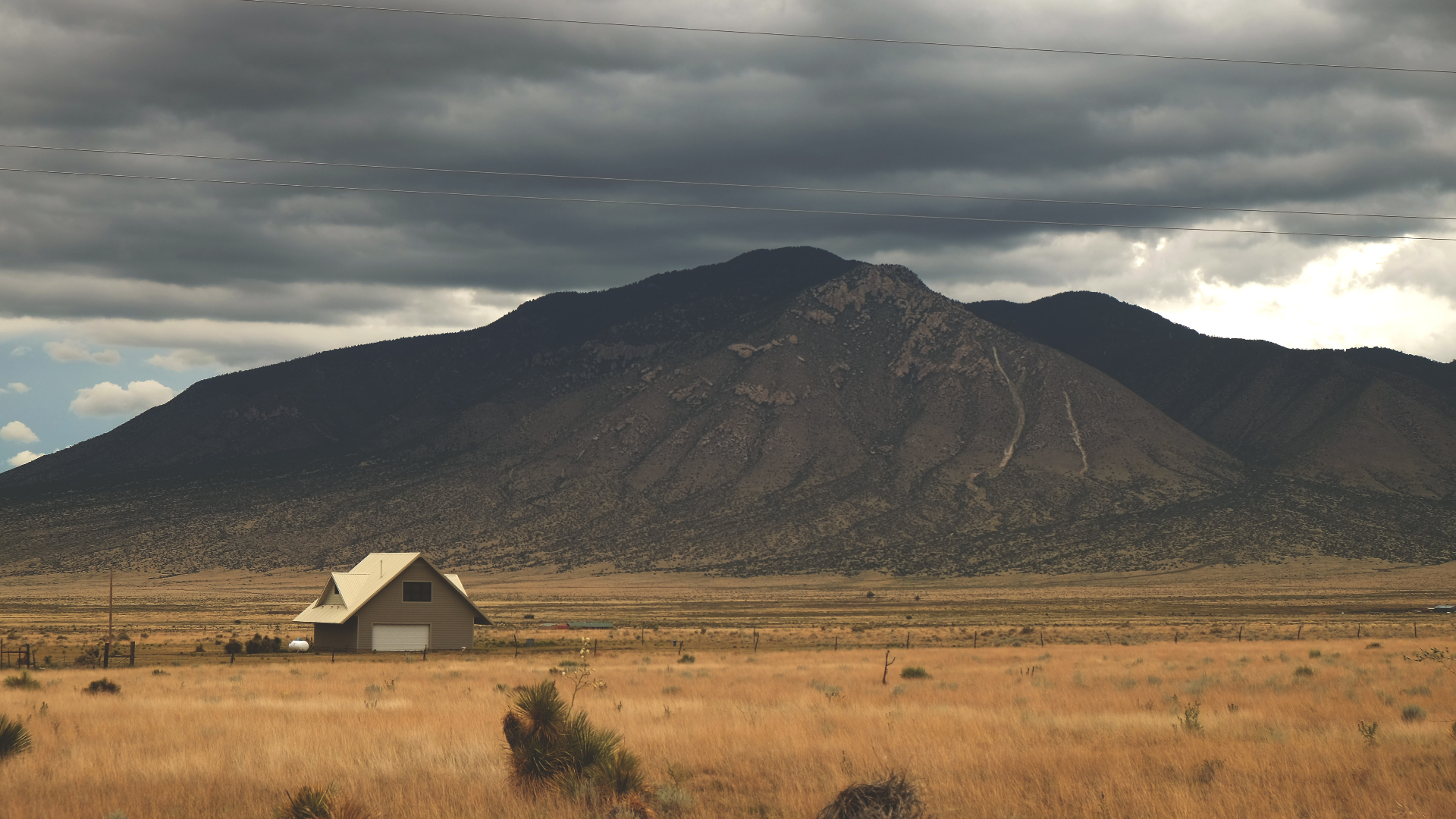 House in front of a mountain under cloudy sky HD Wallpaper