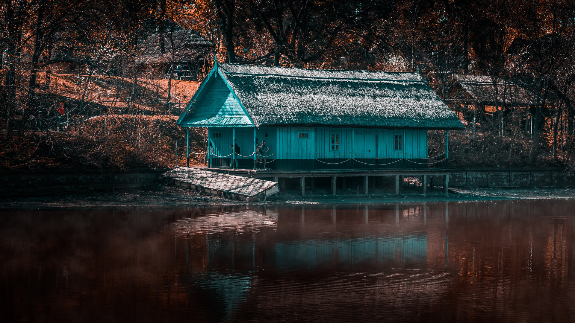 Blue house on stilts by the water with trees HD Wallpaper