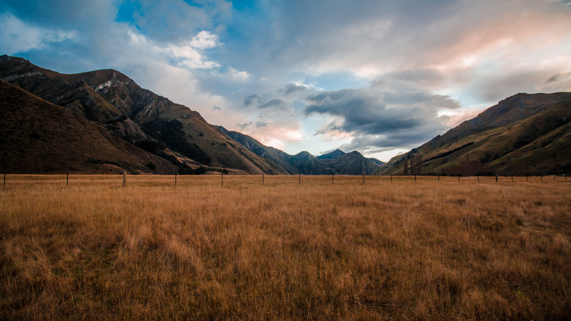 Mountains and dry grass field under cloudy sky HD Wallpaper