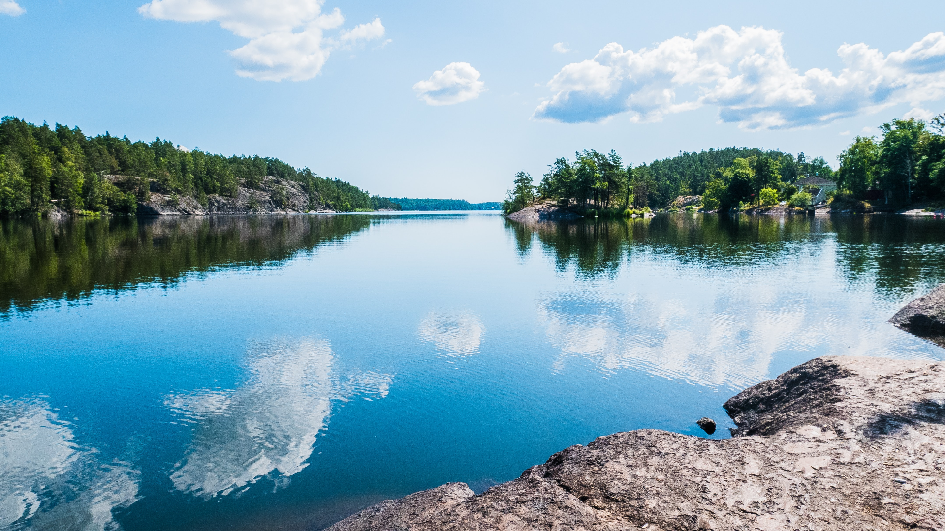 Lake landscape with rocky shores and trees under a cloudy sky HD Wallpaper