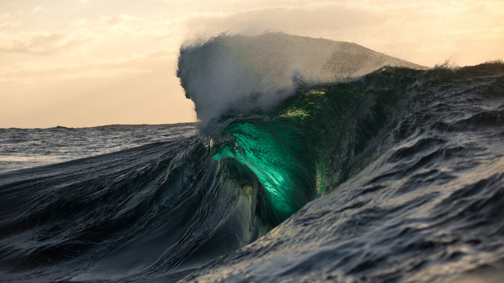 Glowing green wave crashing in the ocean at sunset HD Wallpaper