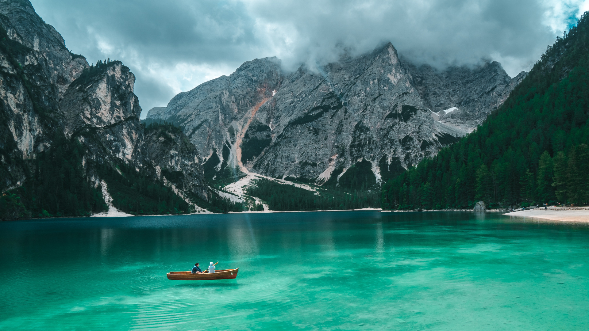 Two people in a boat on a clear lake with mountains HD Wallpaper