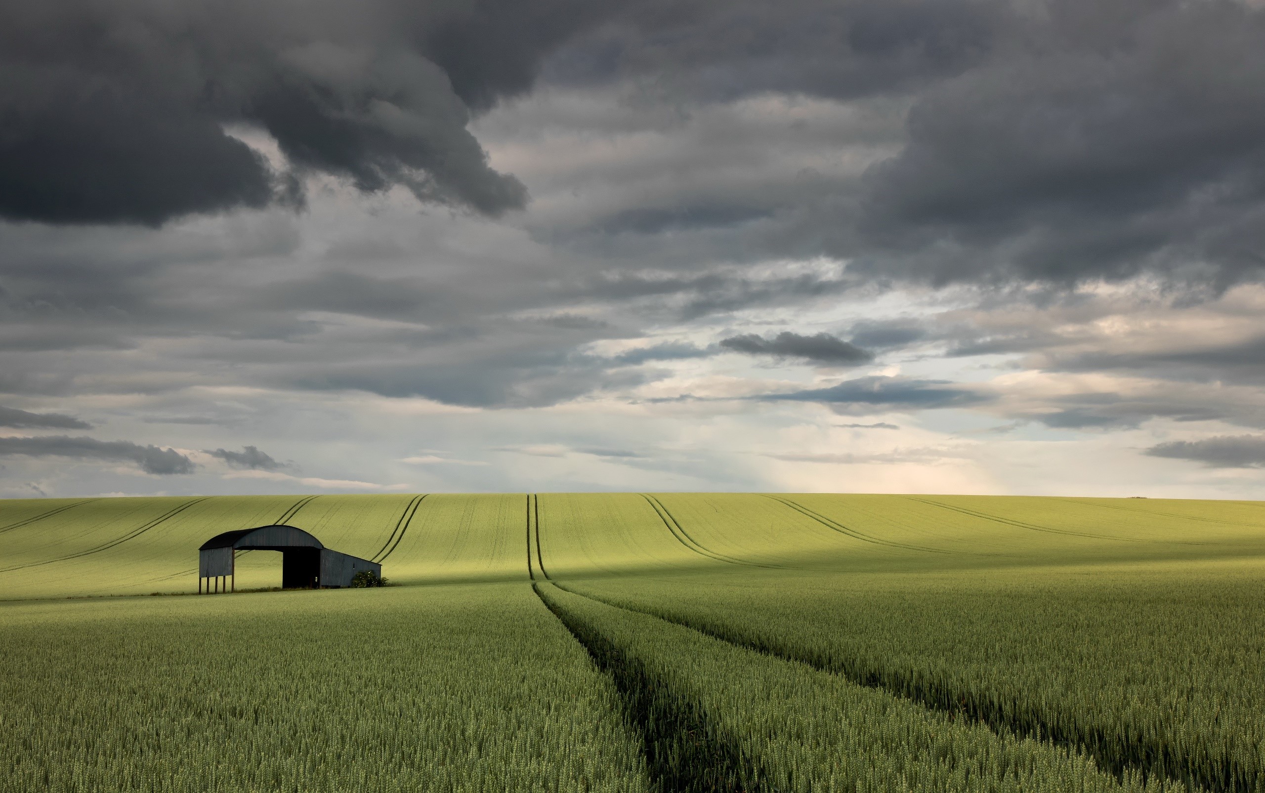 Barn in a green field under a cloudy sky HD Wallpaper