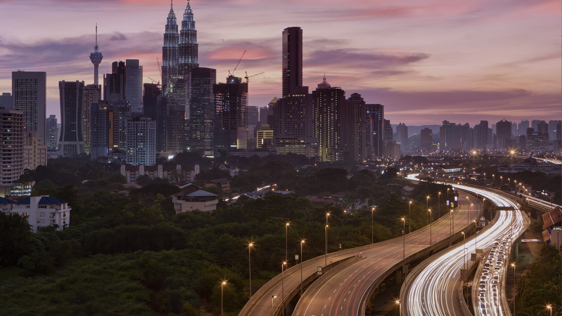 Kuala Lumpur cityscape at sunset with Petronas Towers and highway HD Wallpaper