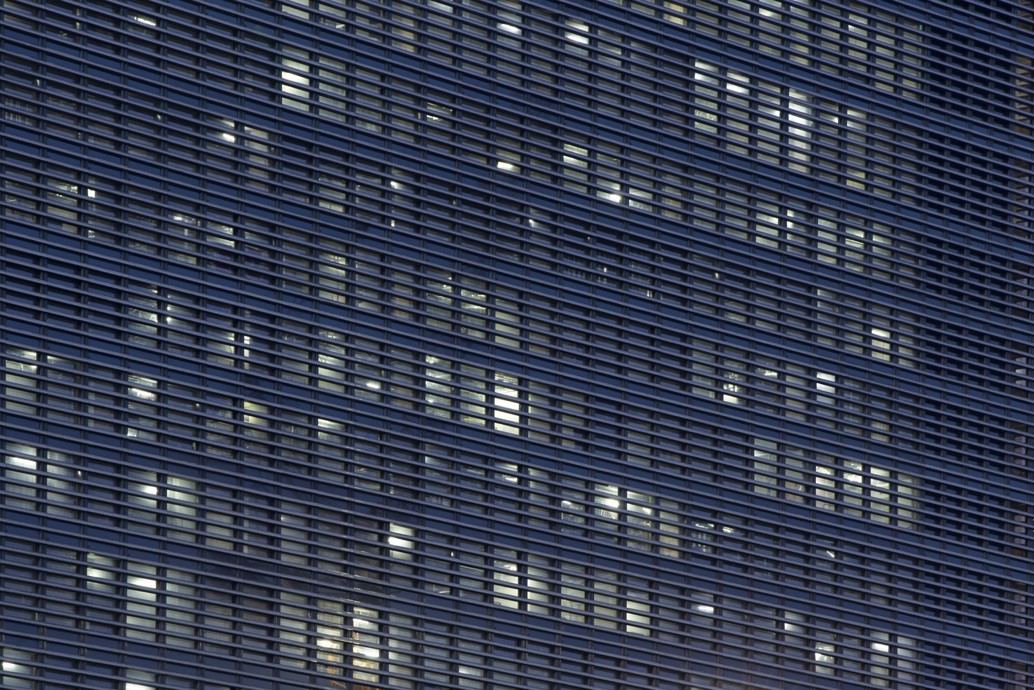 Modern building facade with horizontal louvers and illuminated windows HD Wallpaper