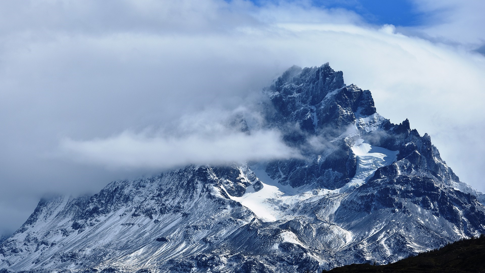 Snowy mountain peak shrouded in clouds in Patagonia HD Wallpaper
