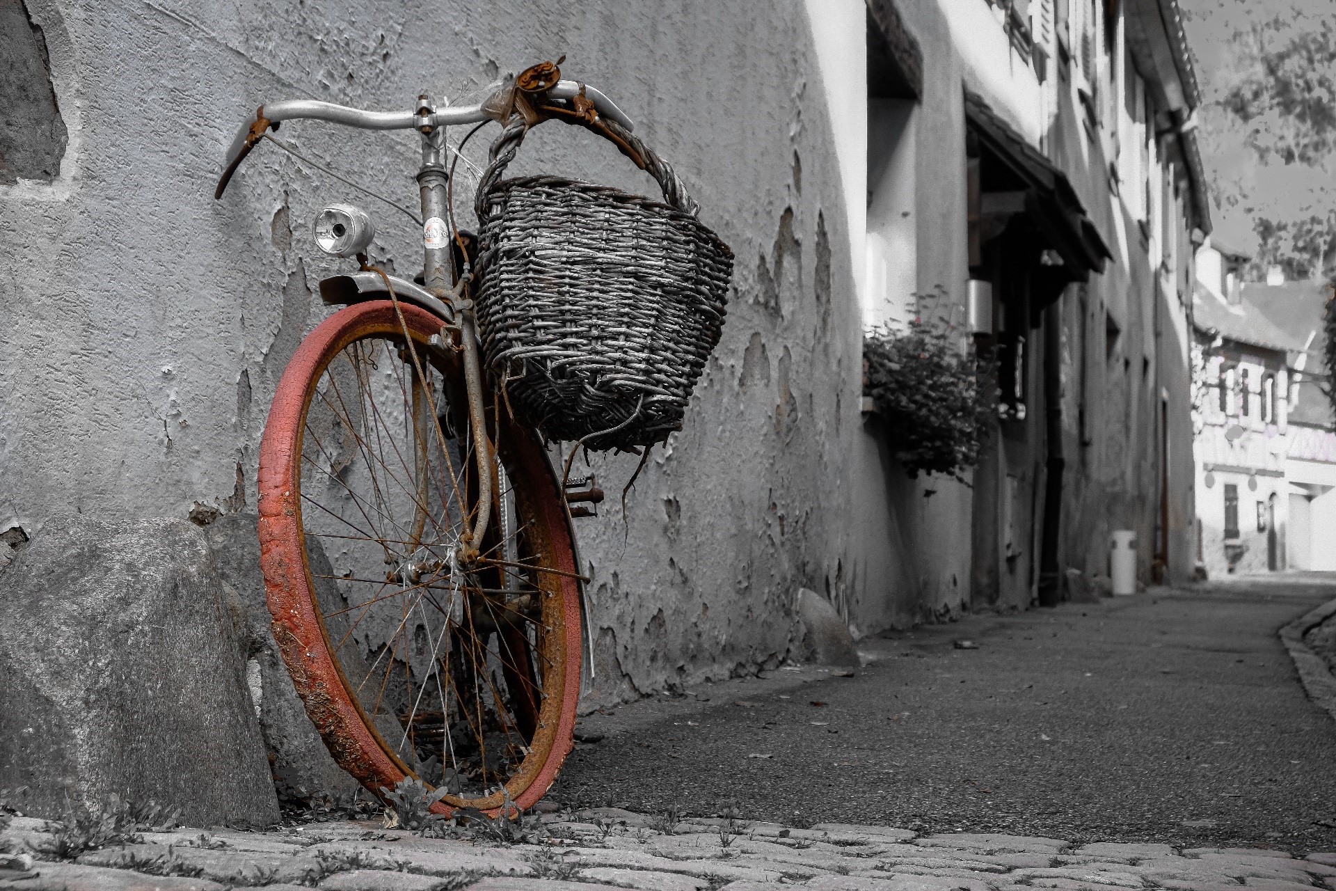 Old bicycle with basket leaning against a weathered wall in a European town HD Wallpaper