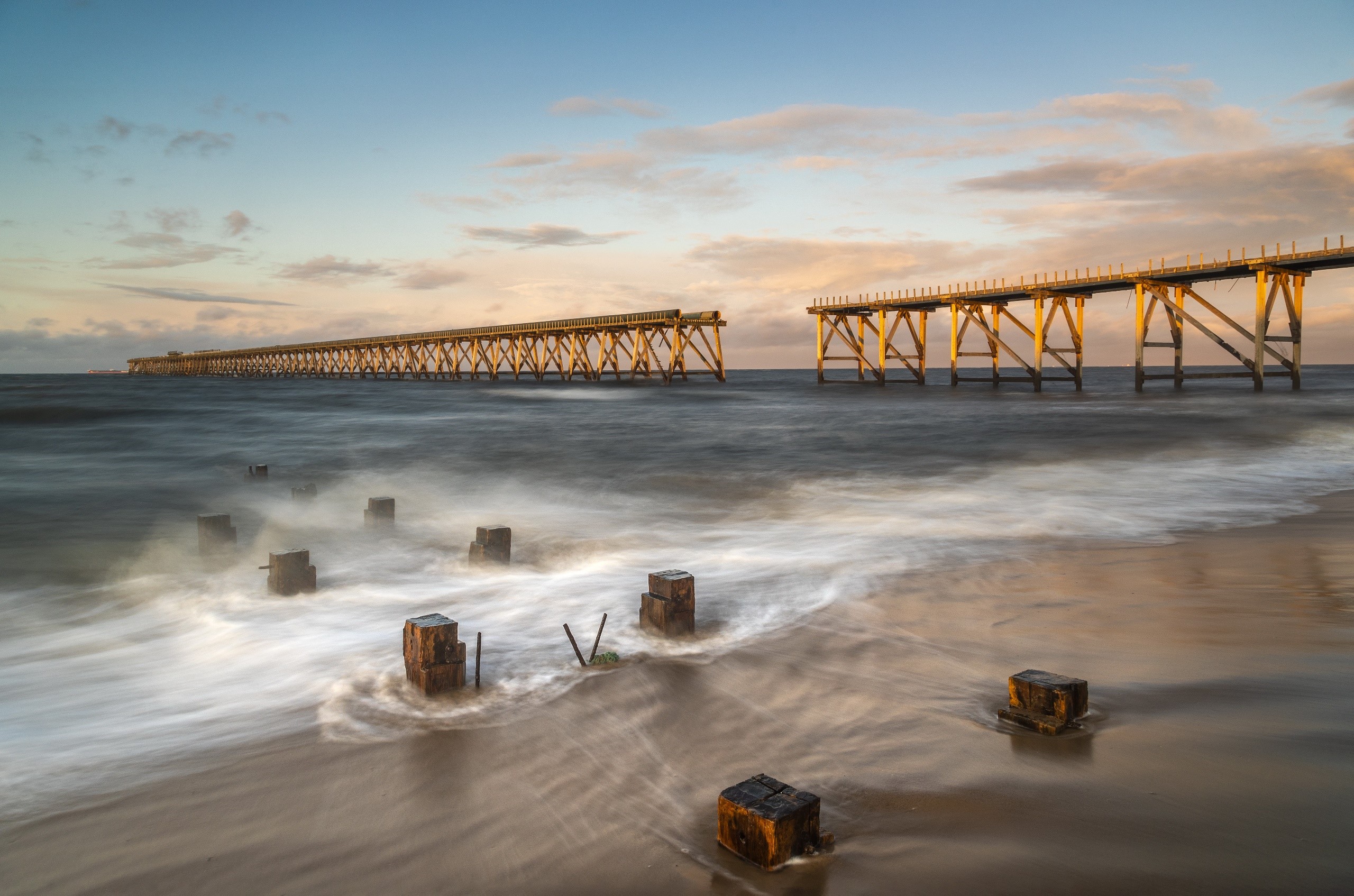 Broken wooden pier on a beach at sunset HD Wallpaper