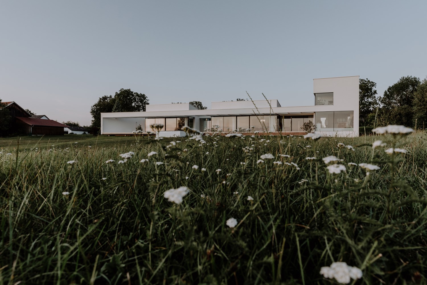 Modern white house with large windows in a grassy field HD Wallpaper