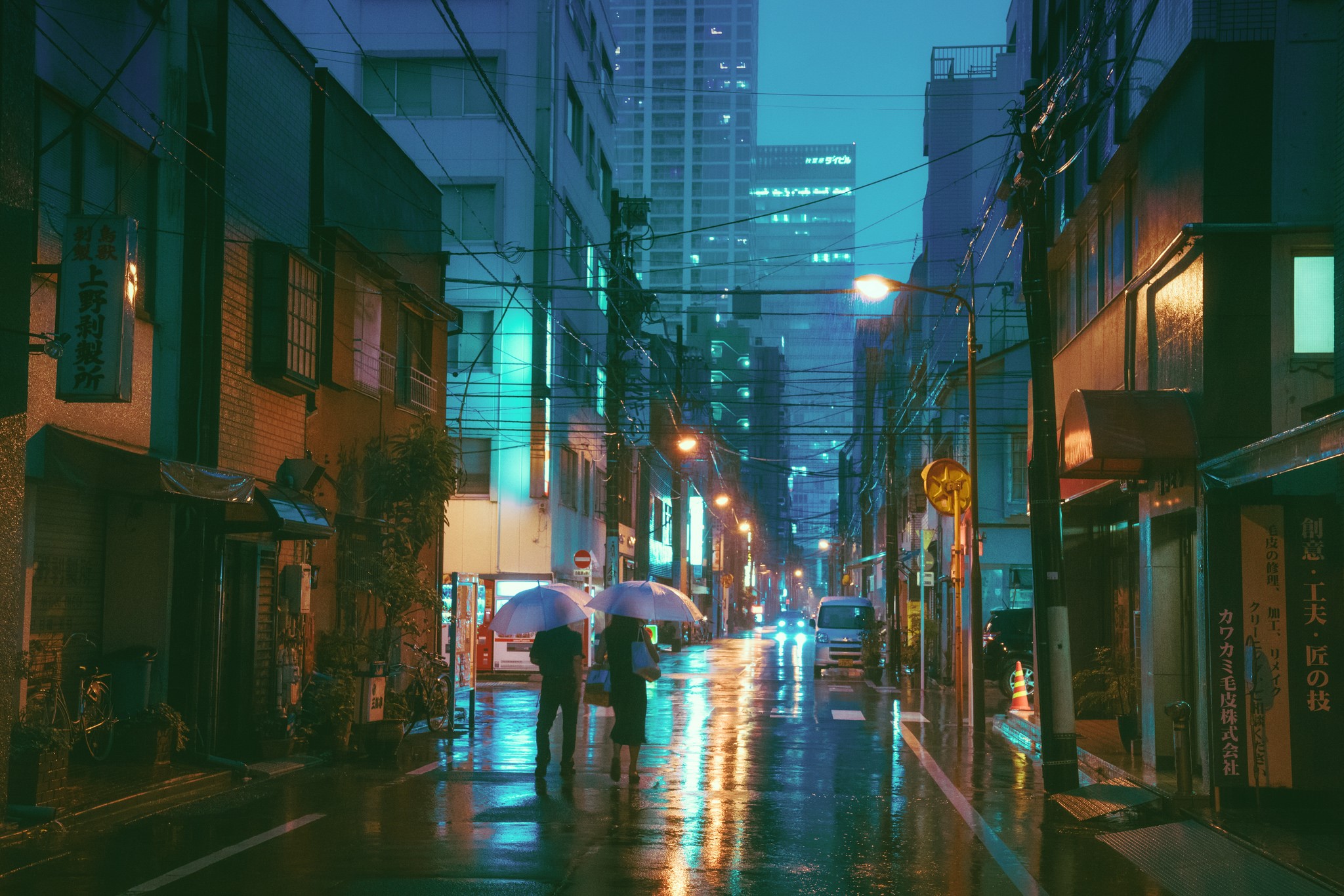 Two people with umbrellas walk down a wet city street at night HD Wallpaper